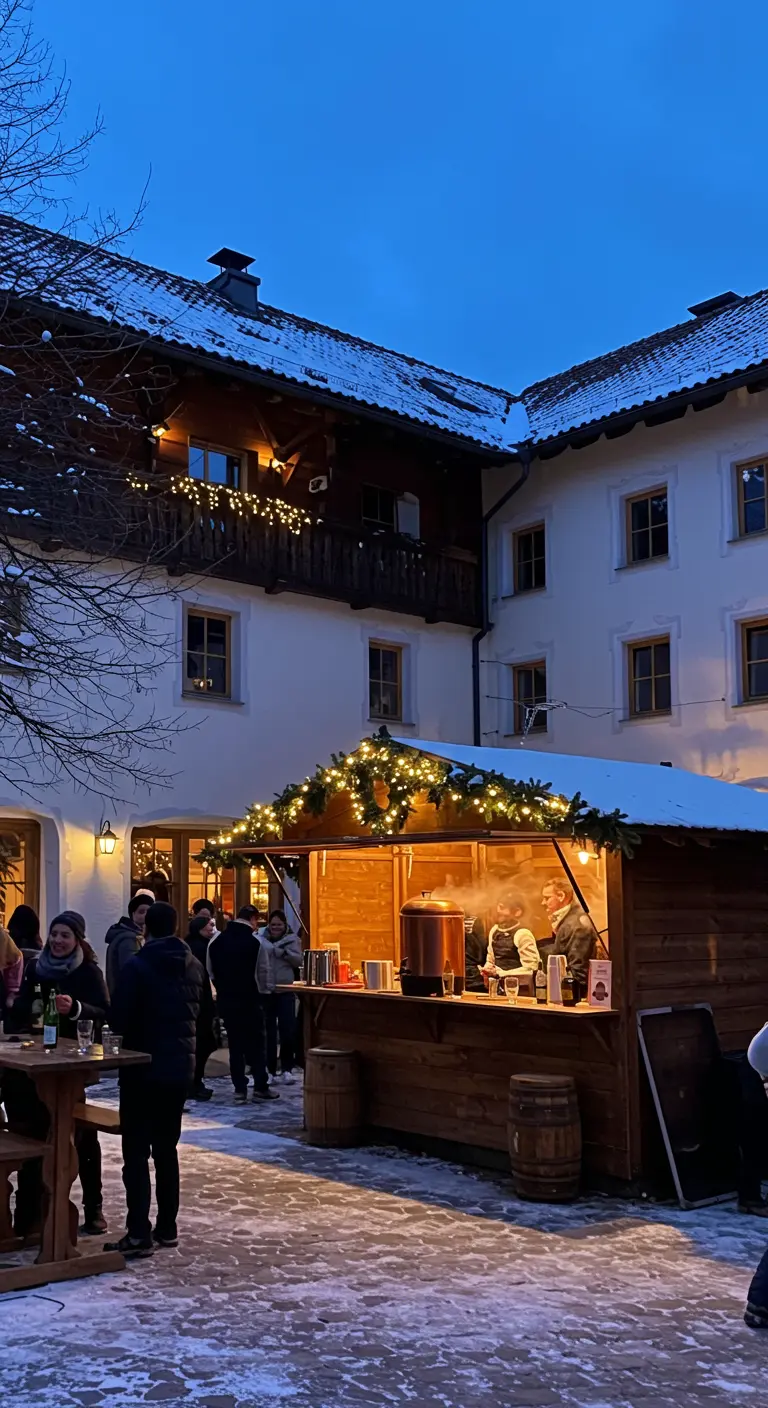 Eine beleuchtete Holzhütte dient als Glühweinstand in einem verschneiten Innenhof.