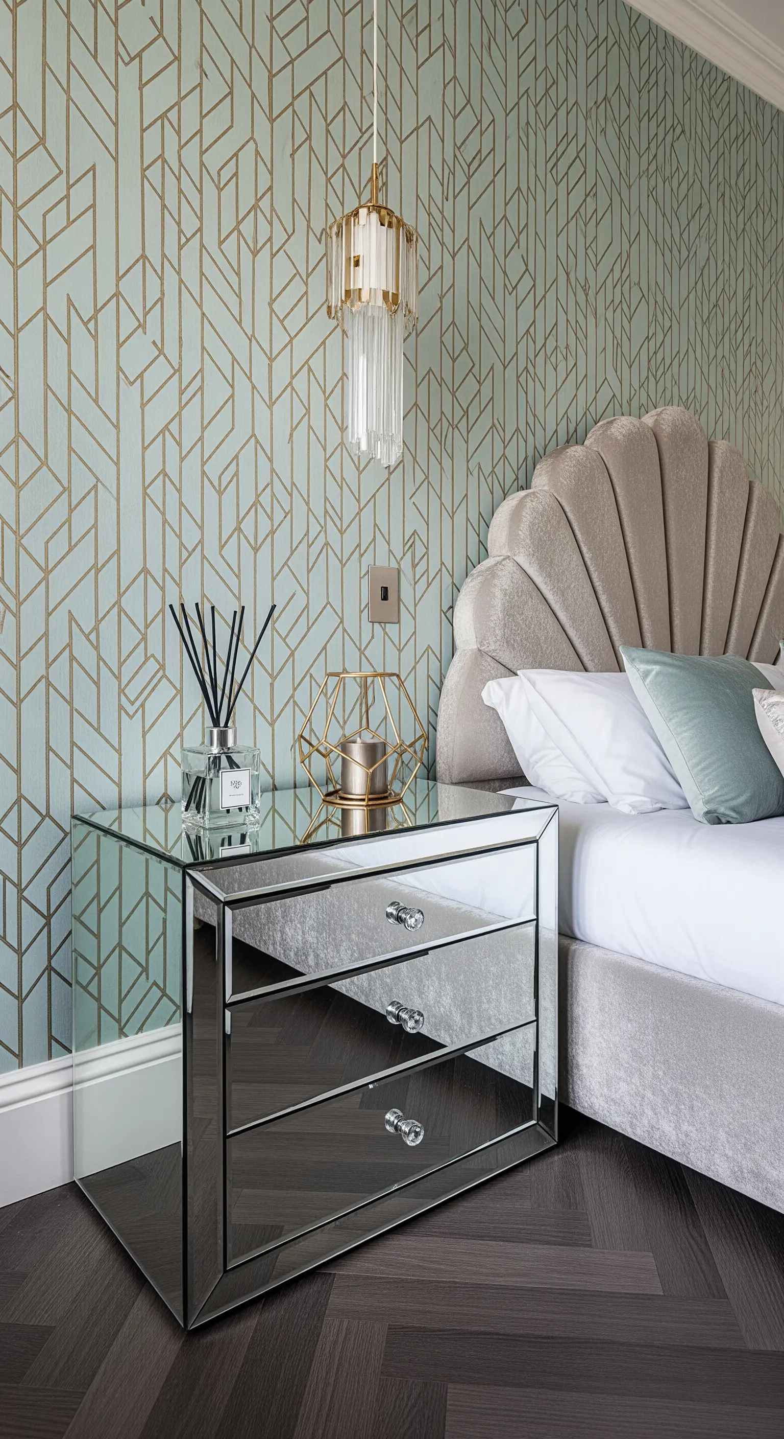 Spiegel-Nachttisch vor geometrischer Tapete mit Diffuser