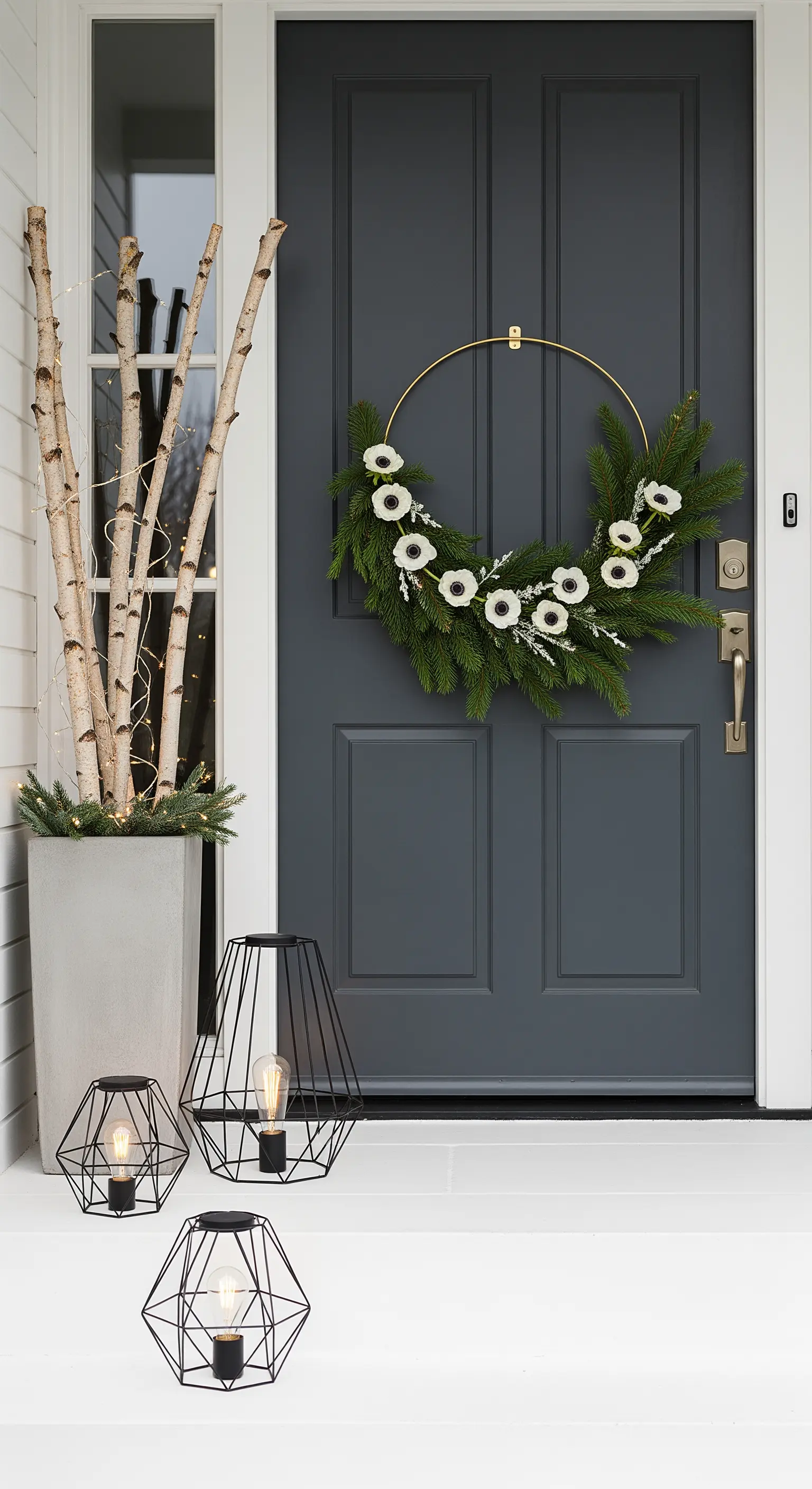 Graue Tür mit modernem Goldring-Kranz und Birkenstämmen