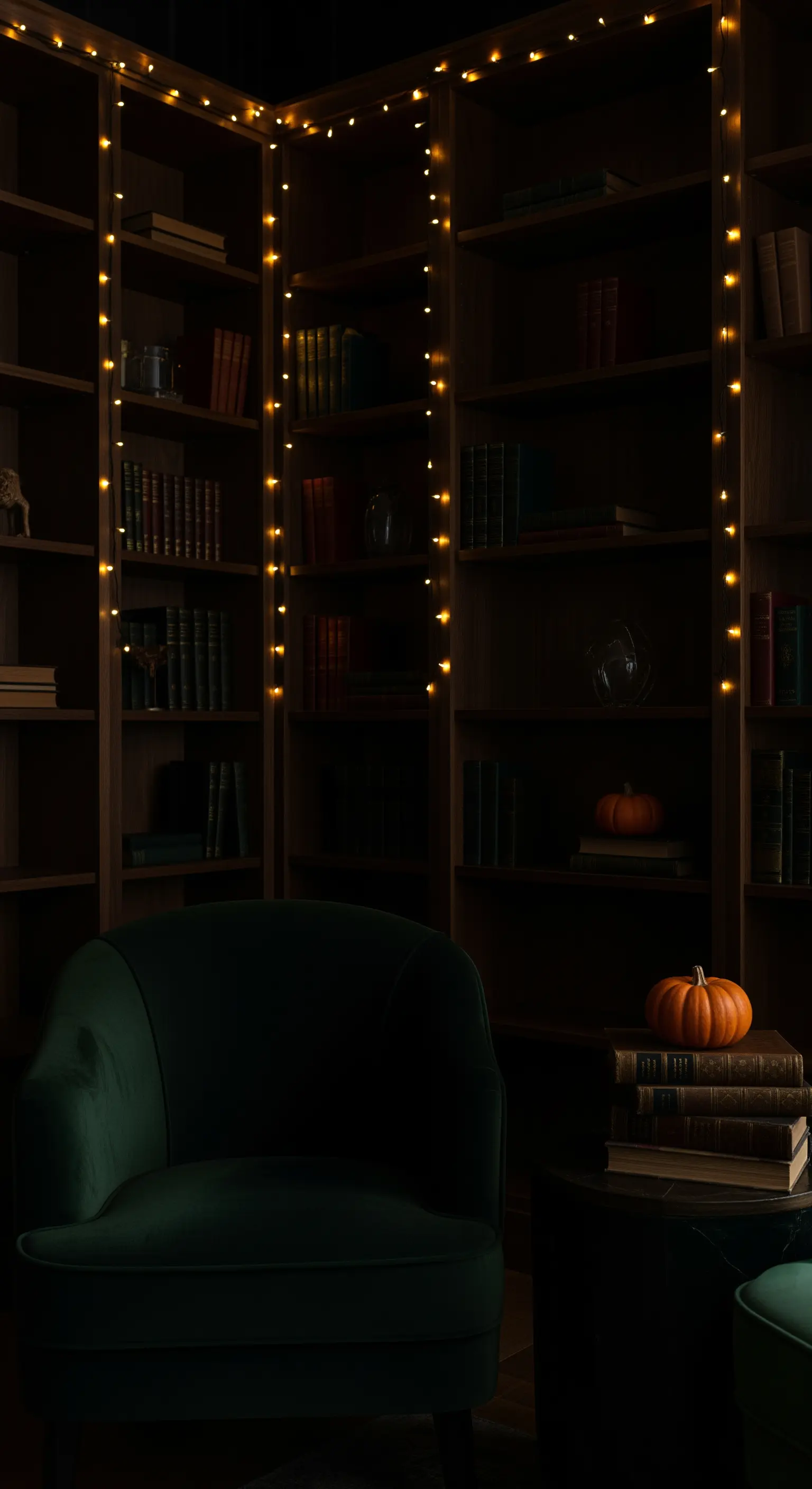 Dunkles Bücherregal mit vertikalen Lichterketten, grünem Samtsessel und minimalistischer Kürbisdeko