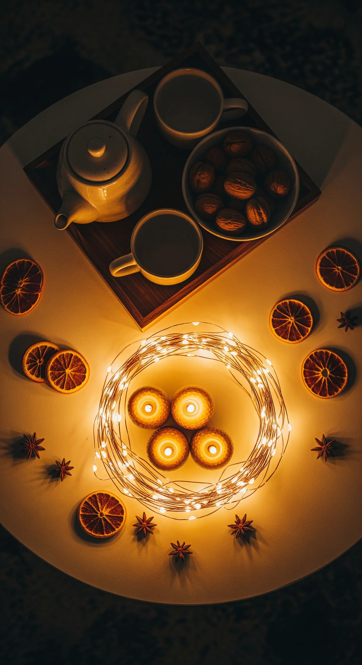 Draufsicht auf runden Tisch mit Teetablett, Nüssen, Lichterkranz und Kerzen