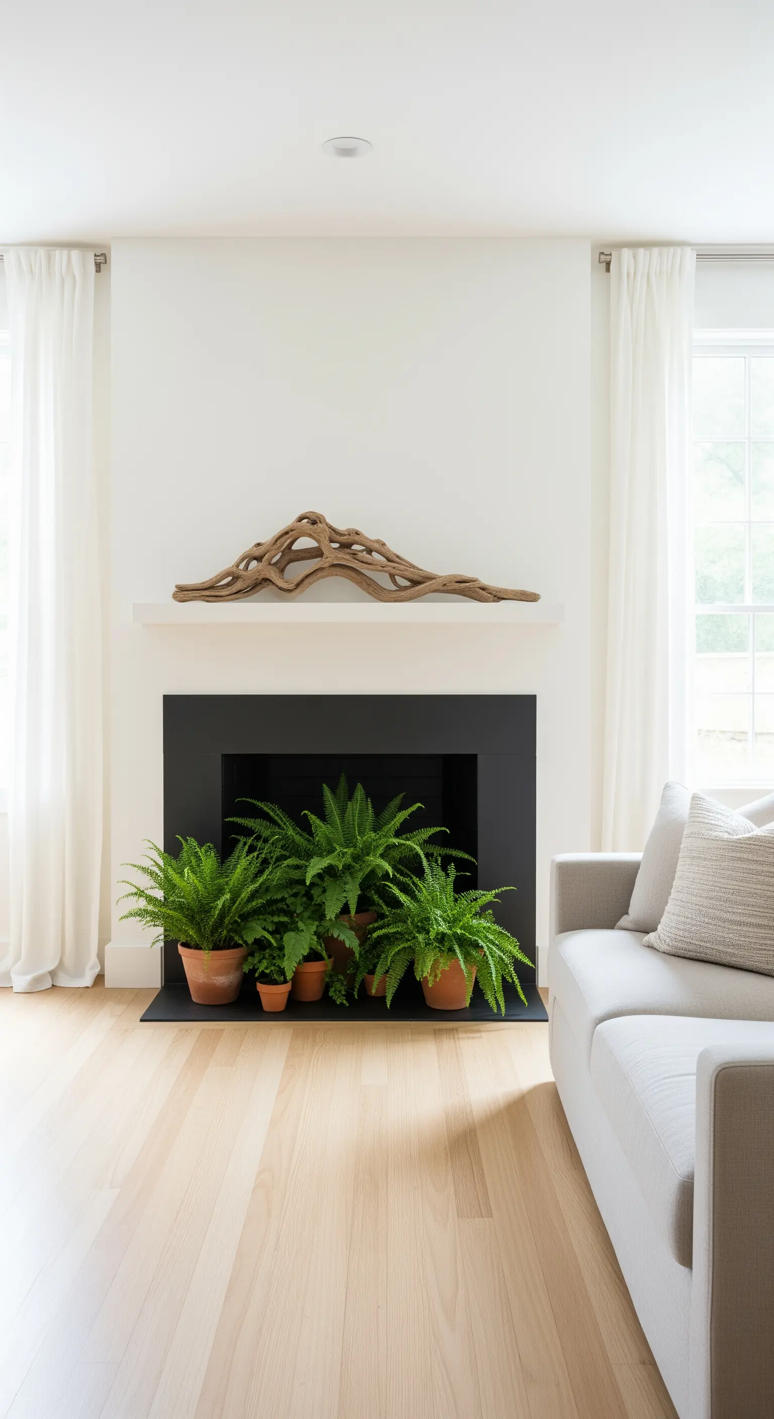 Kaminöffnung gefüllt mit grünen Farnpflanzen, Treibholz oben