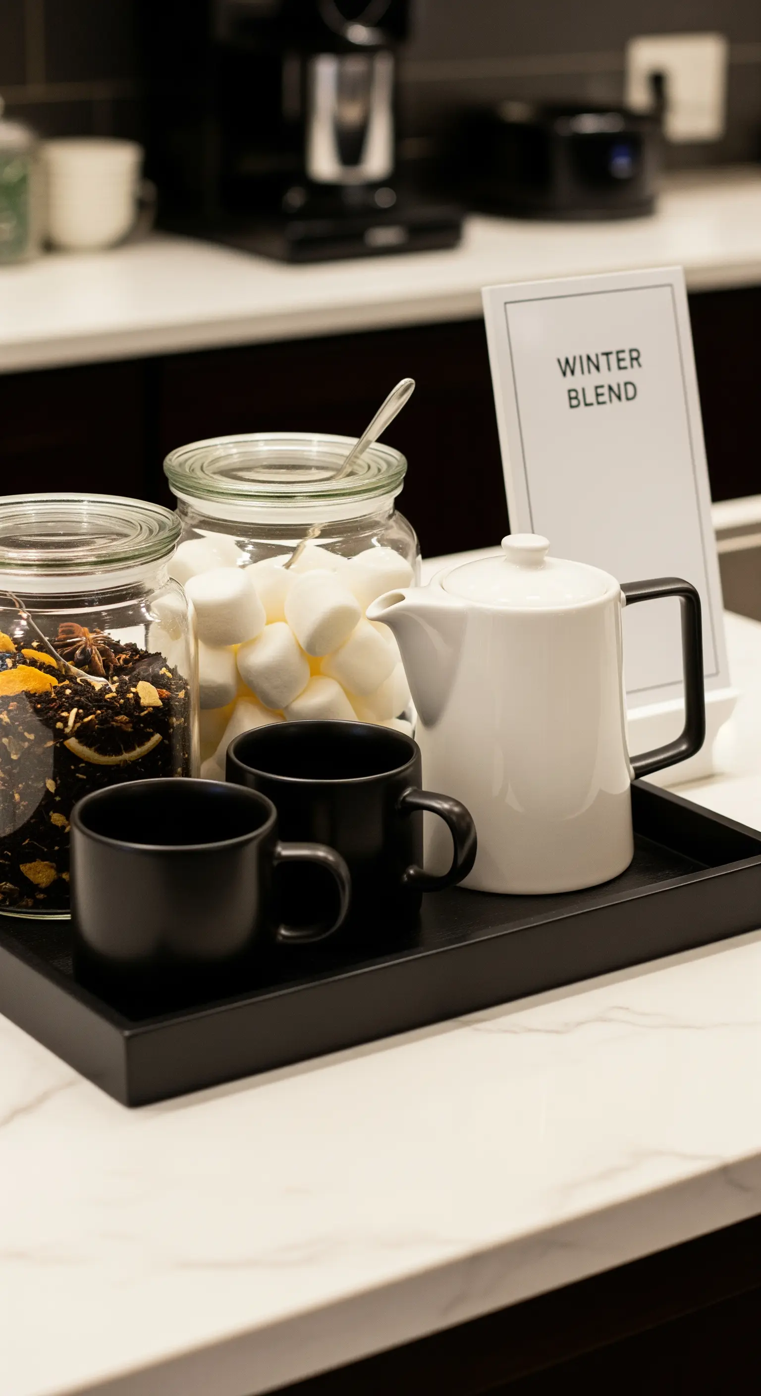 Tablett mit schwarzen Tassen, weißer Kanne und Glasgefäßen mit Marshmallows