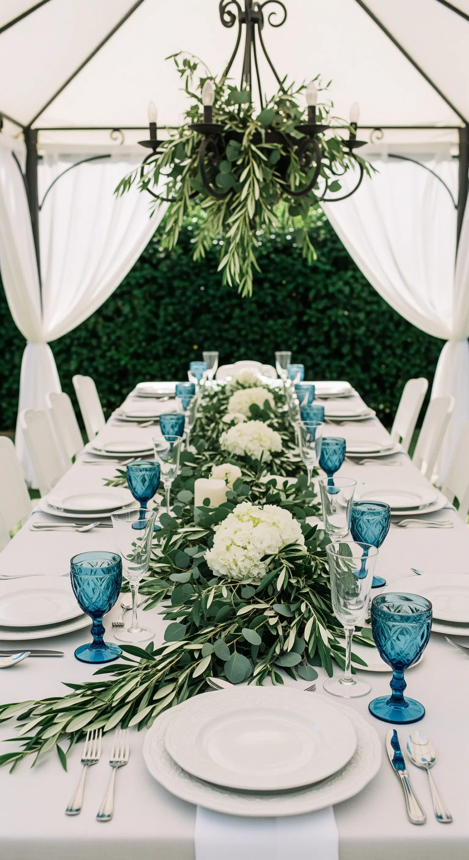 Festliche Tafel unter Pavillon mit weißen Hortensien und blauen Gläsern
