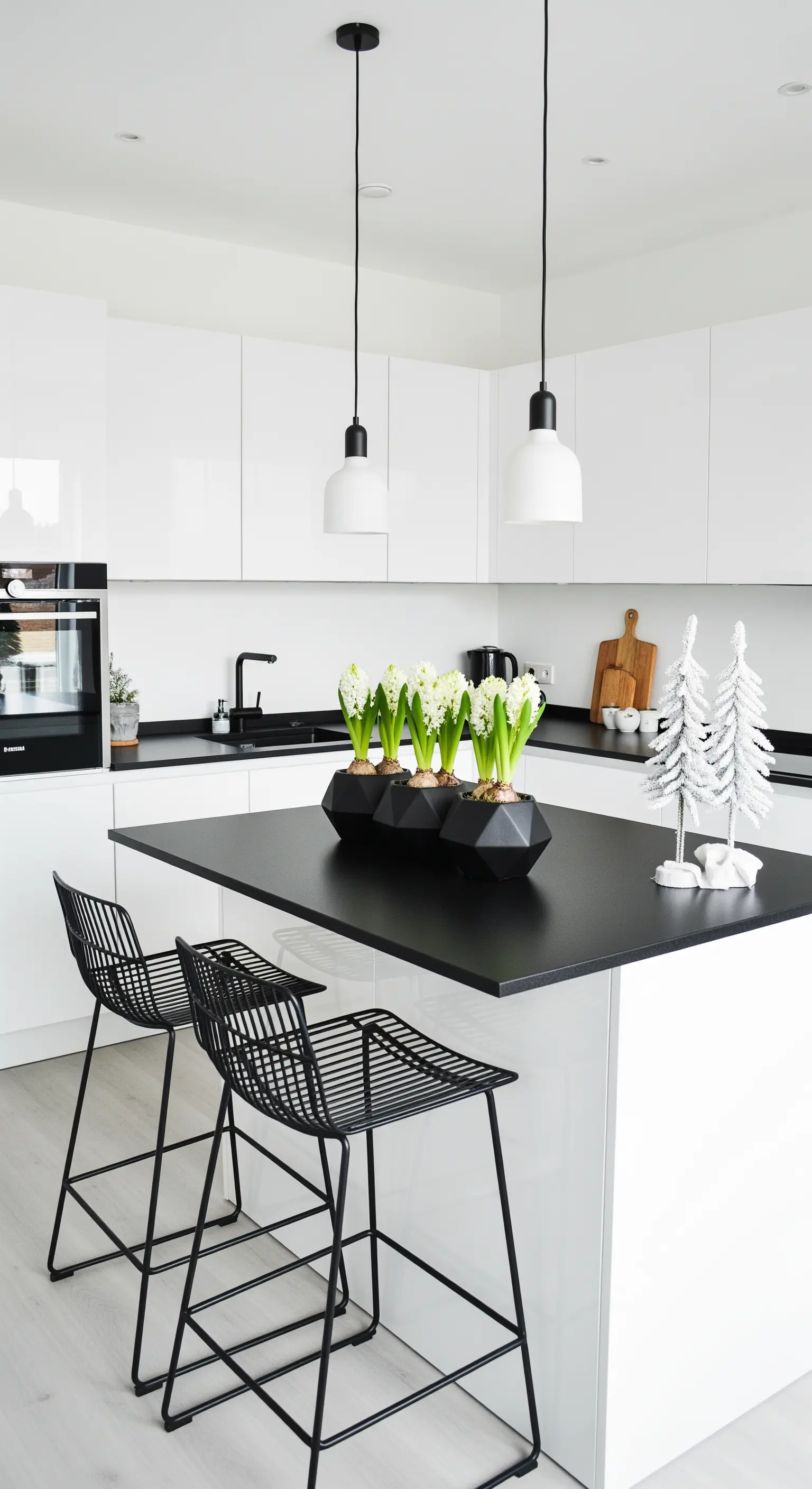 Moderne Küche mit weißen Hyazinthen in schwarzen geometrischen Töpfen auf der Insel