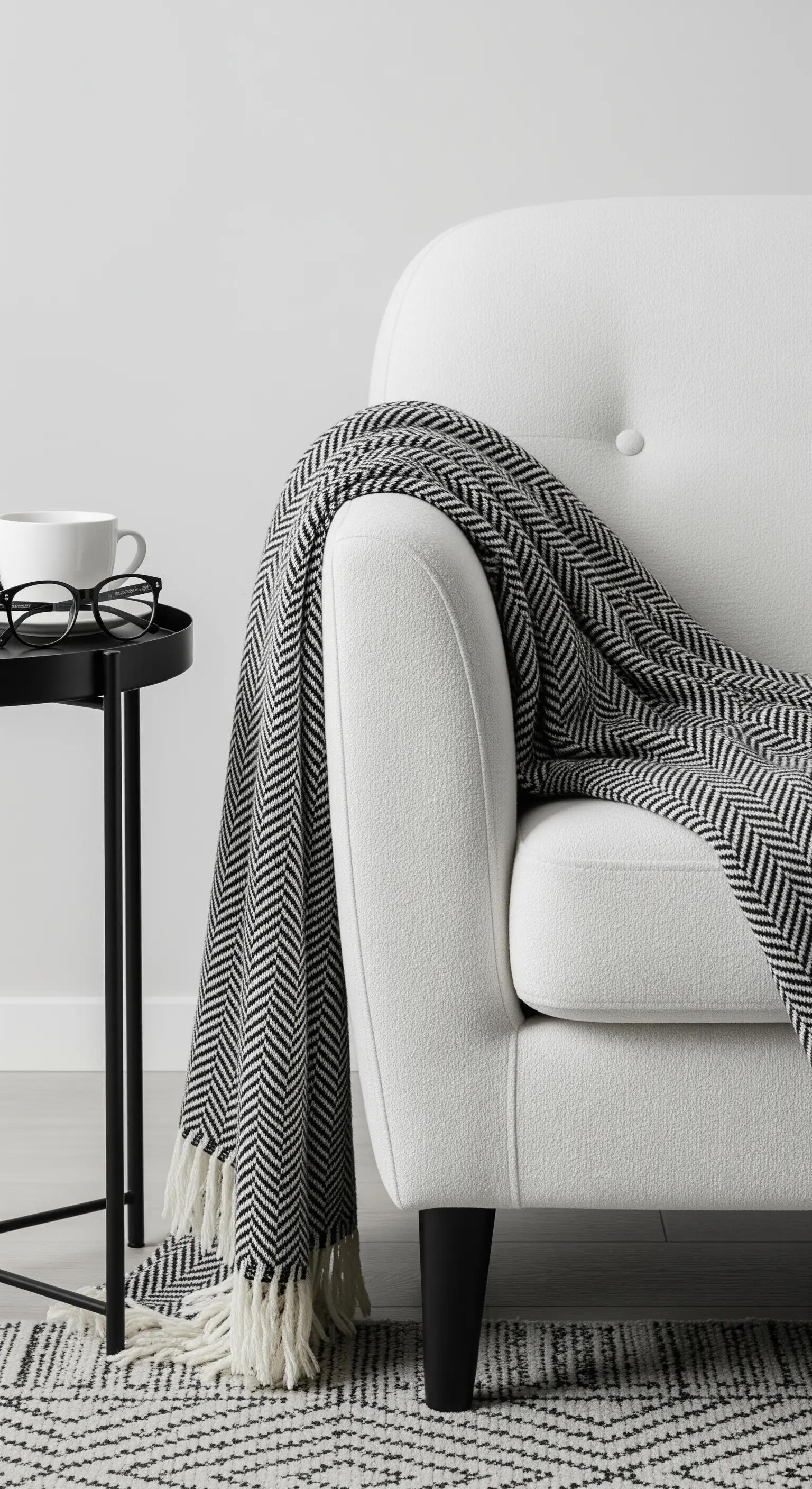 Weißer Sessel mit schwarz-weiß gemusterter Decke und Beistelltisch