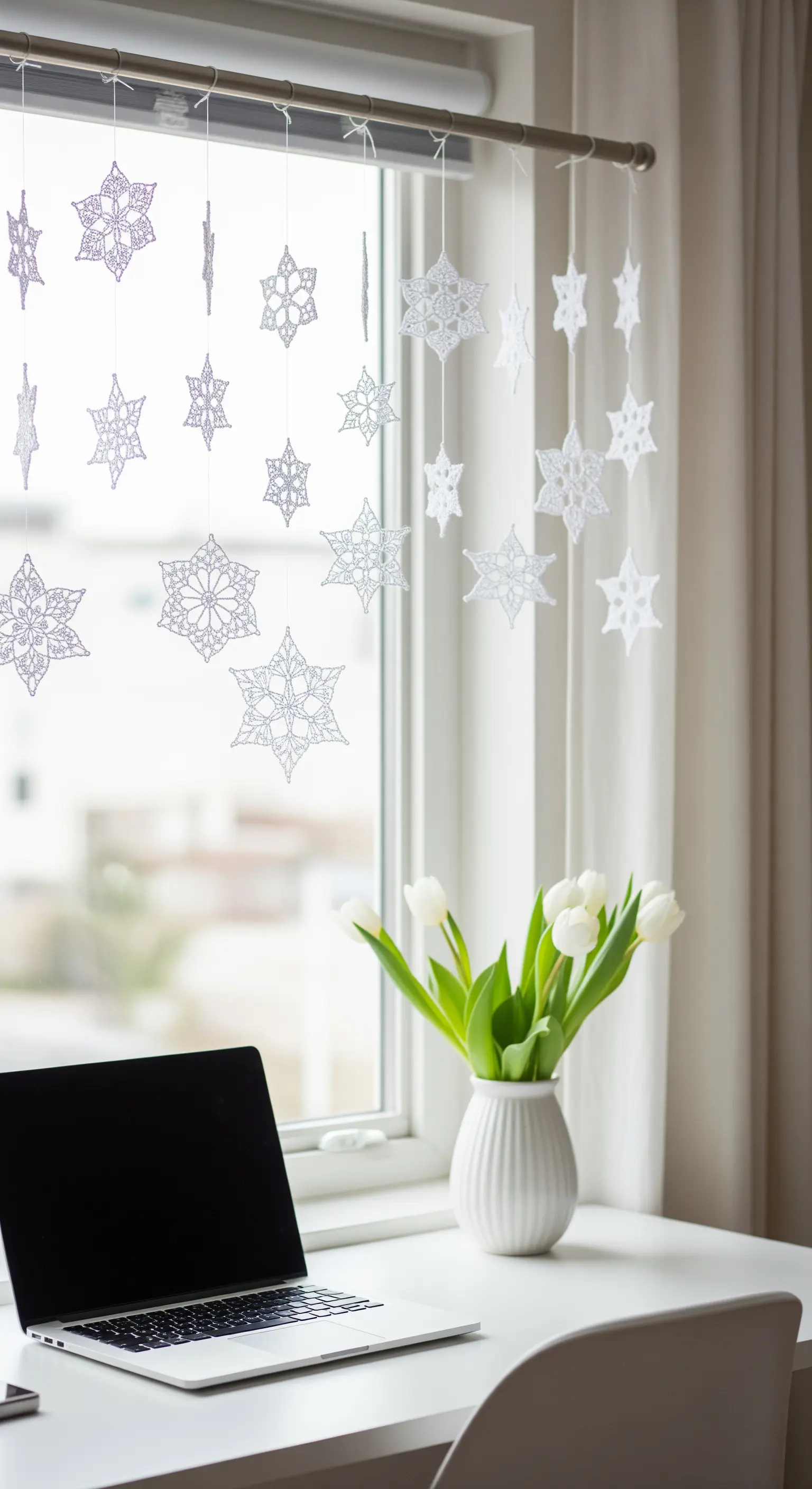 Gehäkelte Schneeflocken im Fenster über dem Schreibtisch