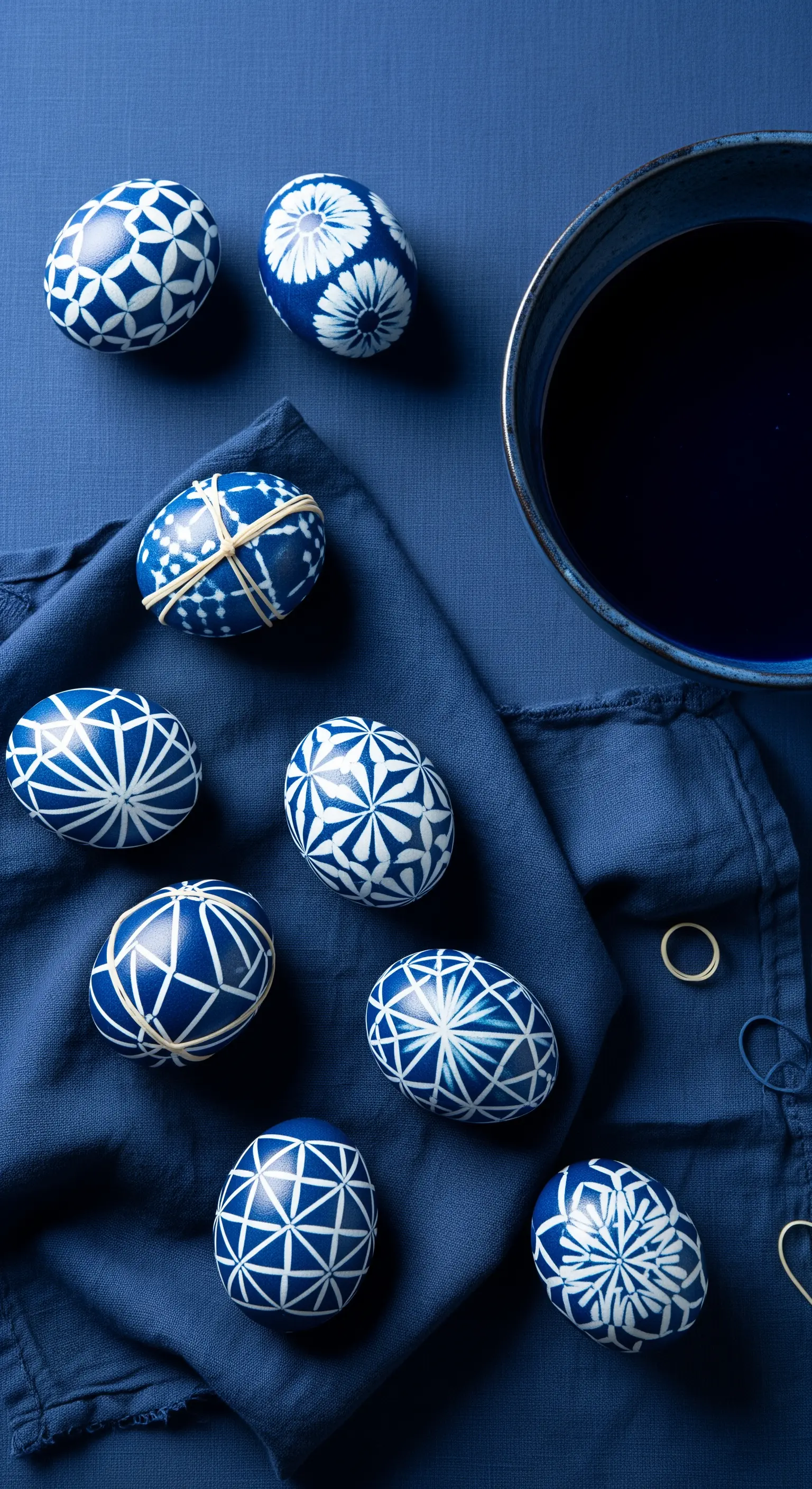 Dunkelblaue Eier mit weißen geometrischen Mustern auf blauem Tuch