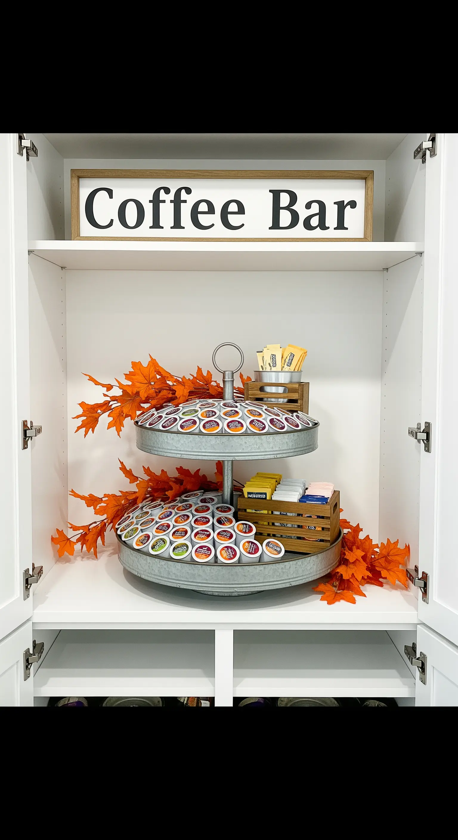 Etagere im Küchenschrank mit sortierten Kaffeekapseln und künstlichem Herbstlaub