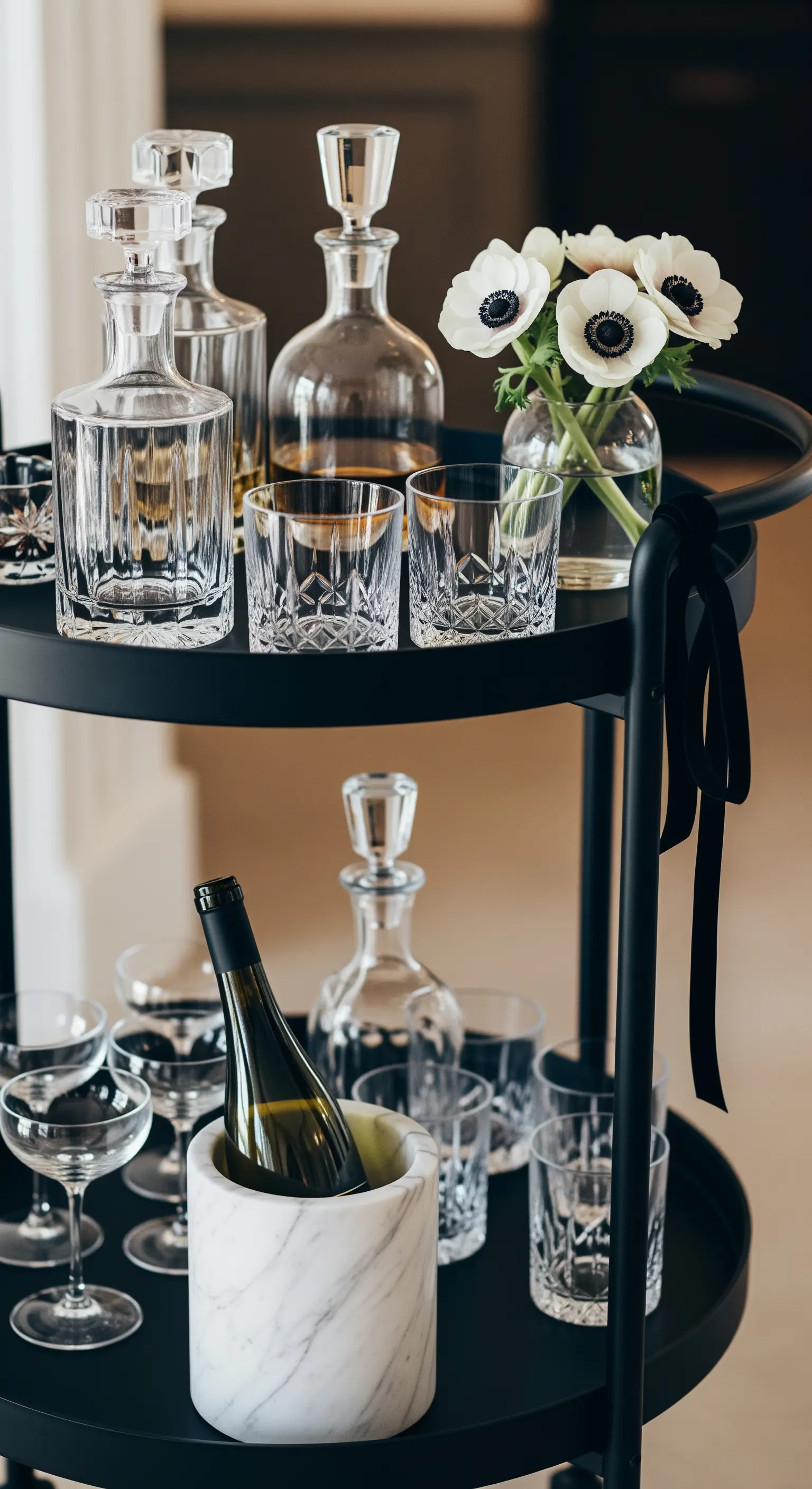 Schwarzer runder Barwagen mit Kristallgläsern und weißen Anemonen in Vase