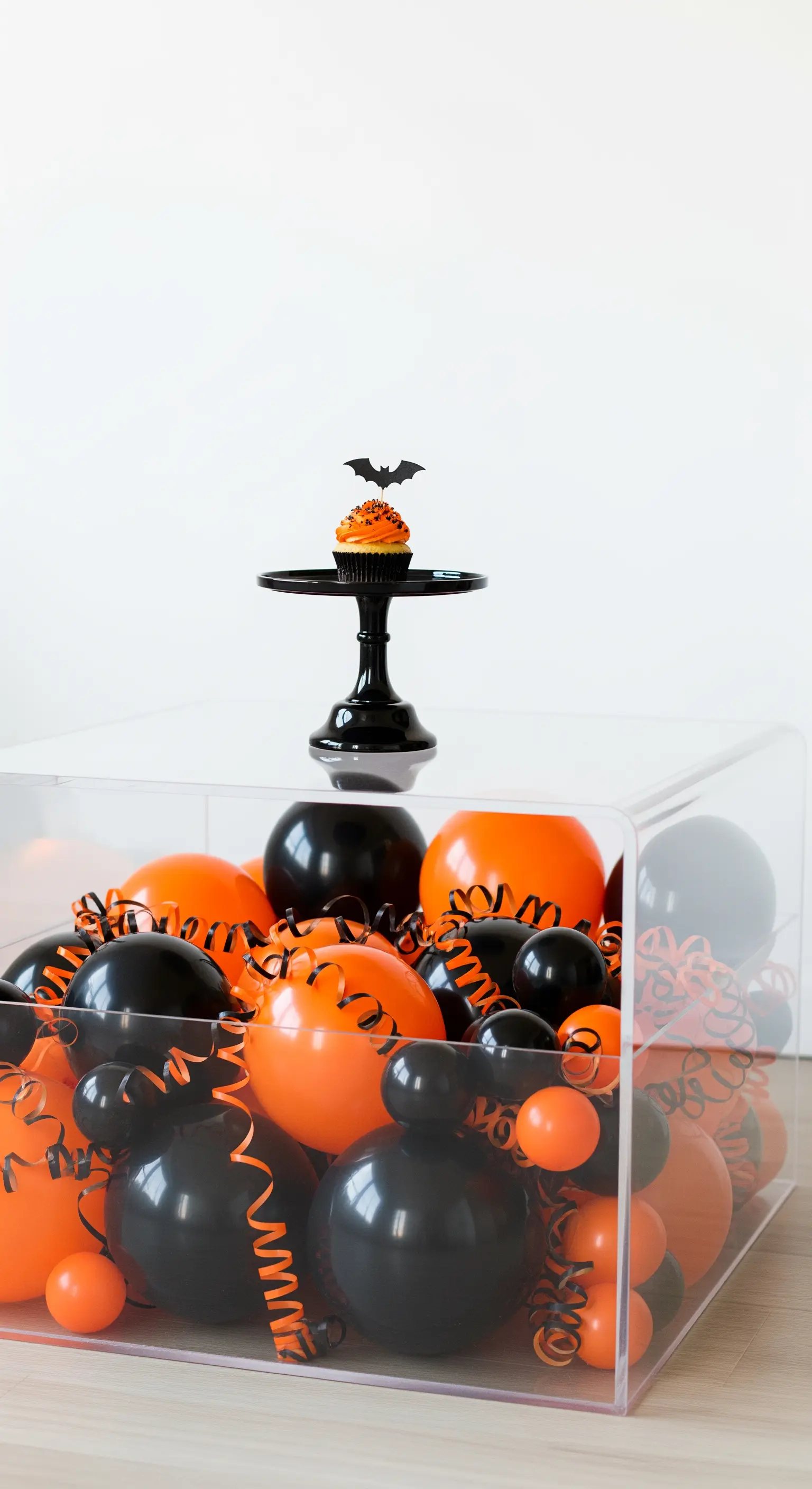 Acrylbox mit Ballons und Cupcake auf schwarzem Ständer