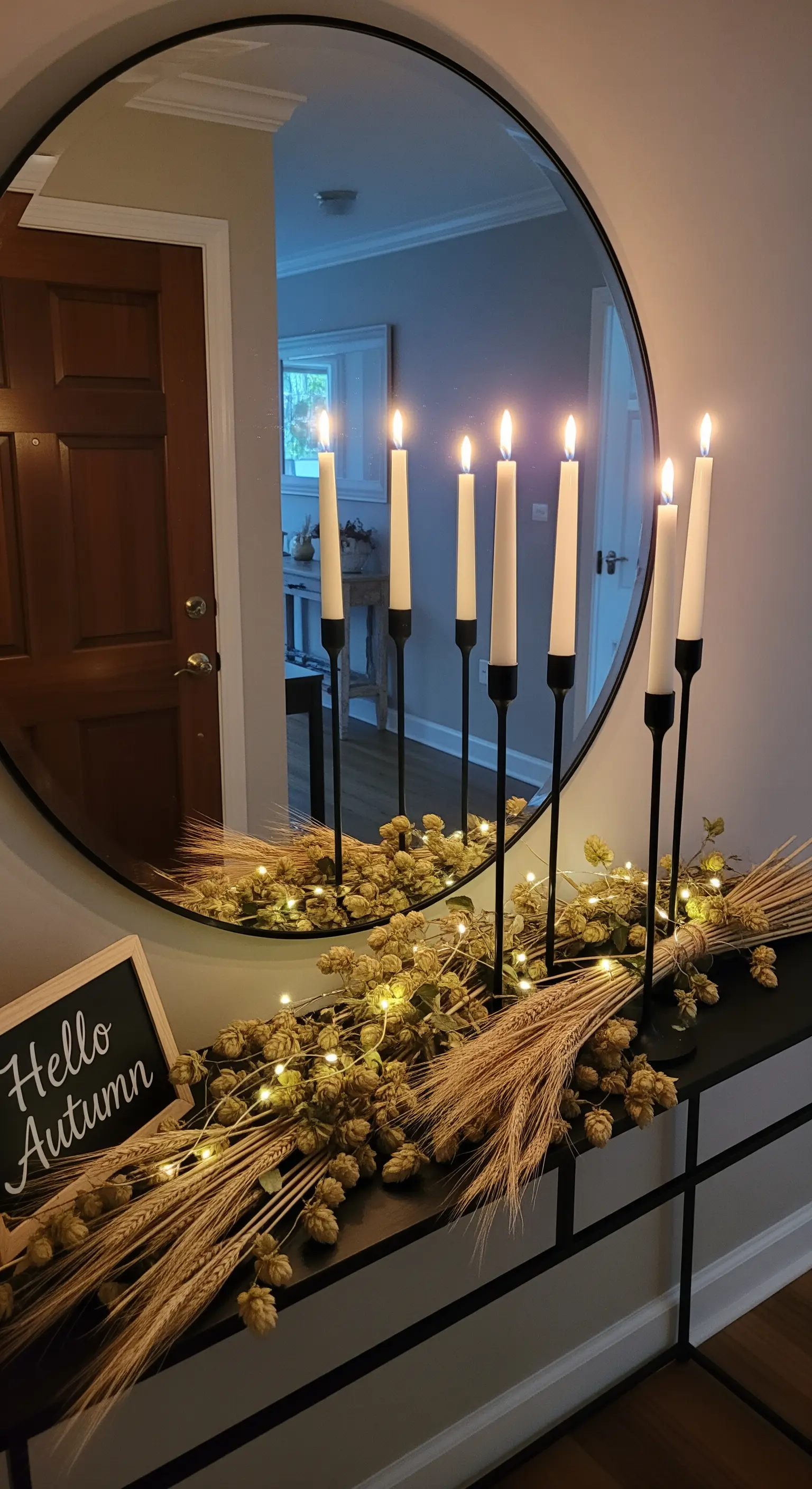 Konsole mit rundem Spiegel, hohen schwarzen Kerzenhaltern und getrocknetem Hopfen