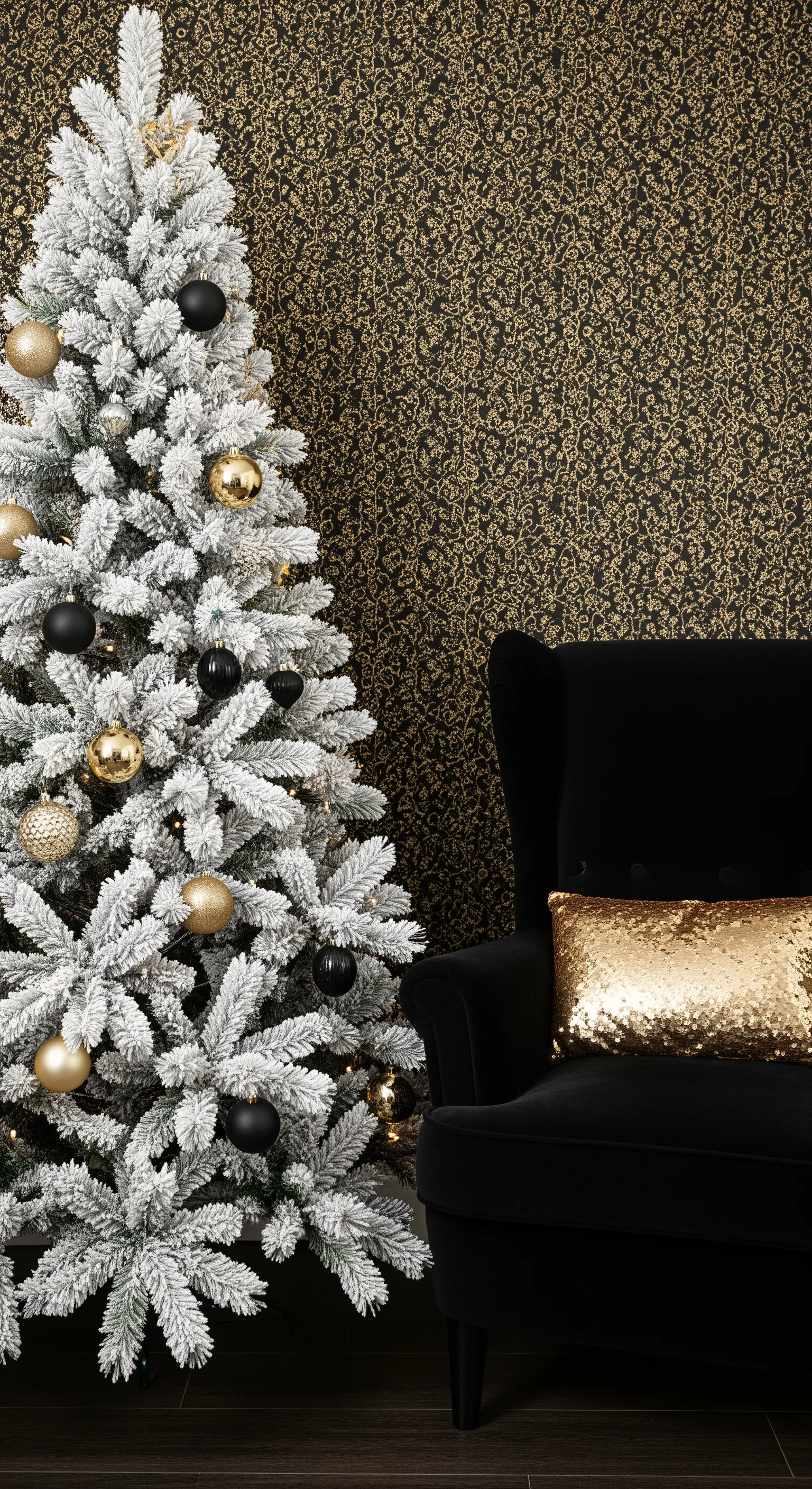 Verschneiter Weihnachtsbaum neben schwarzem Sessel mit Goldkissen