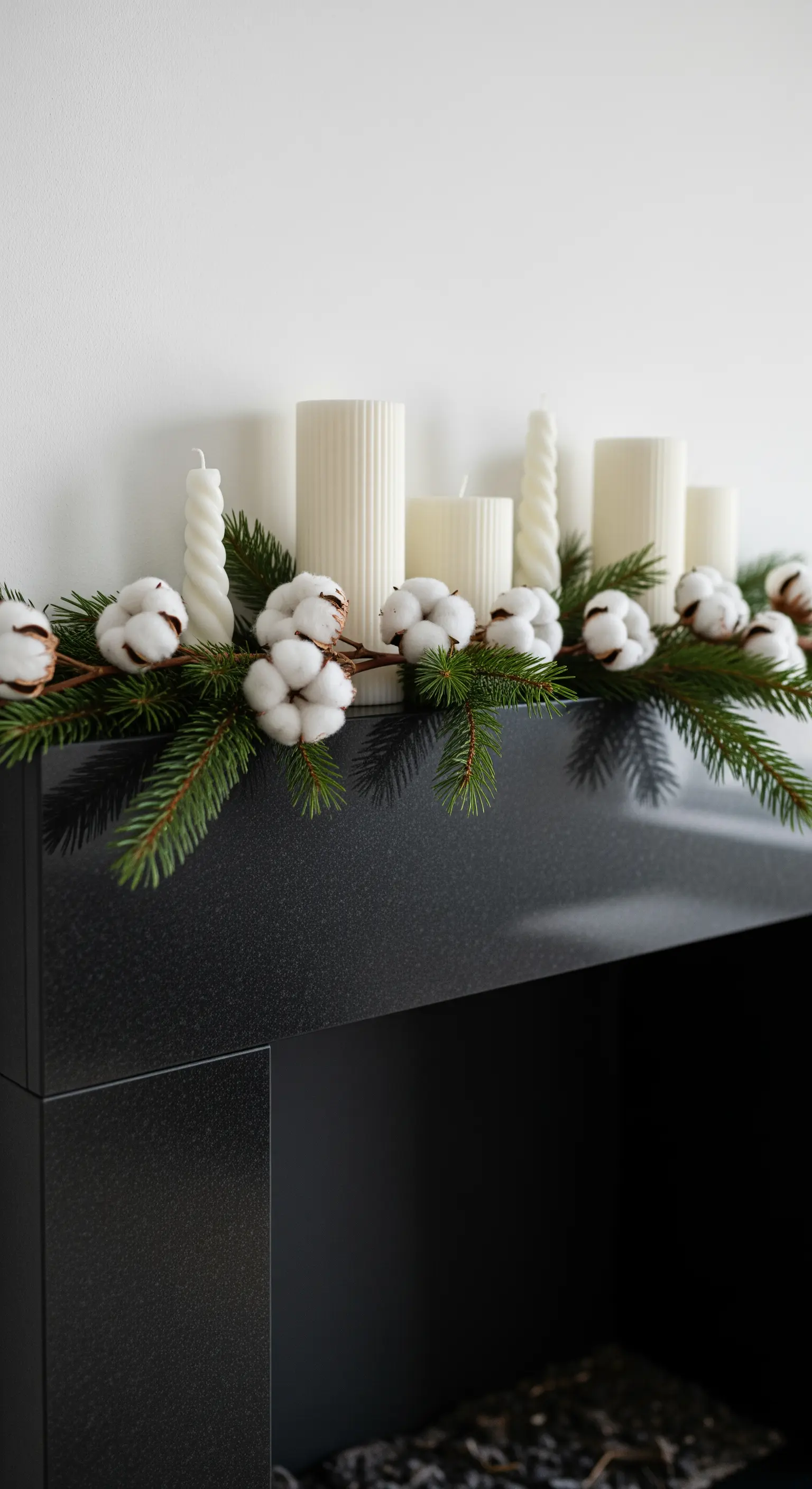 Baumwollzweige und Tanne auf schwarzem Kamin