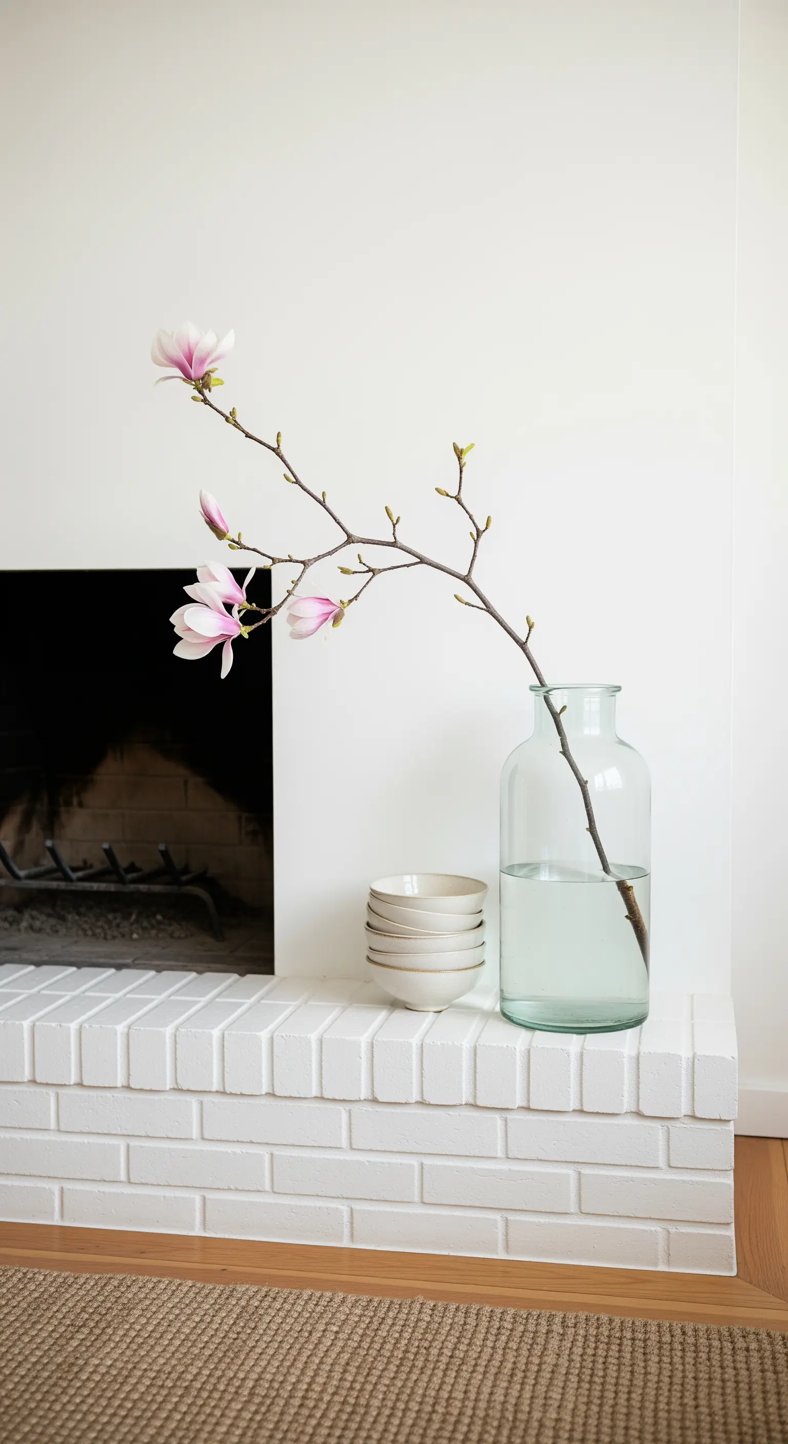 Einzelner Magnolienzweig in Glasvase auf weißem Ziegel-Sims