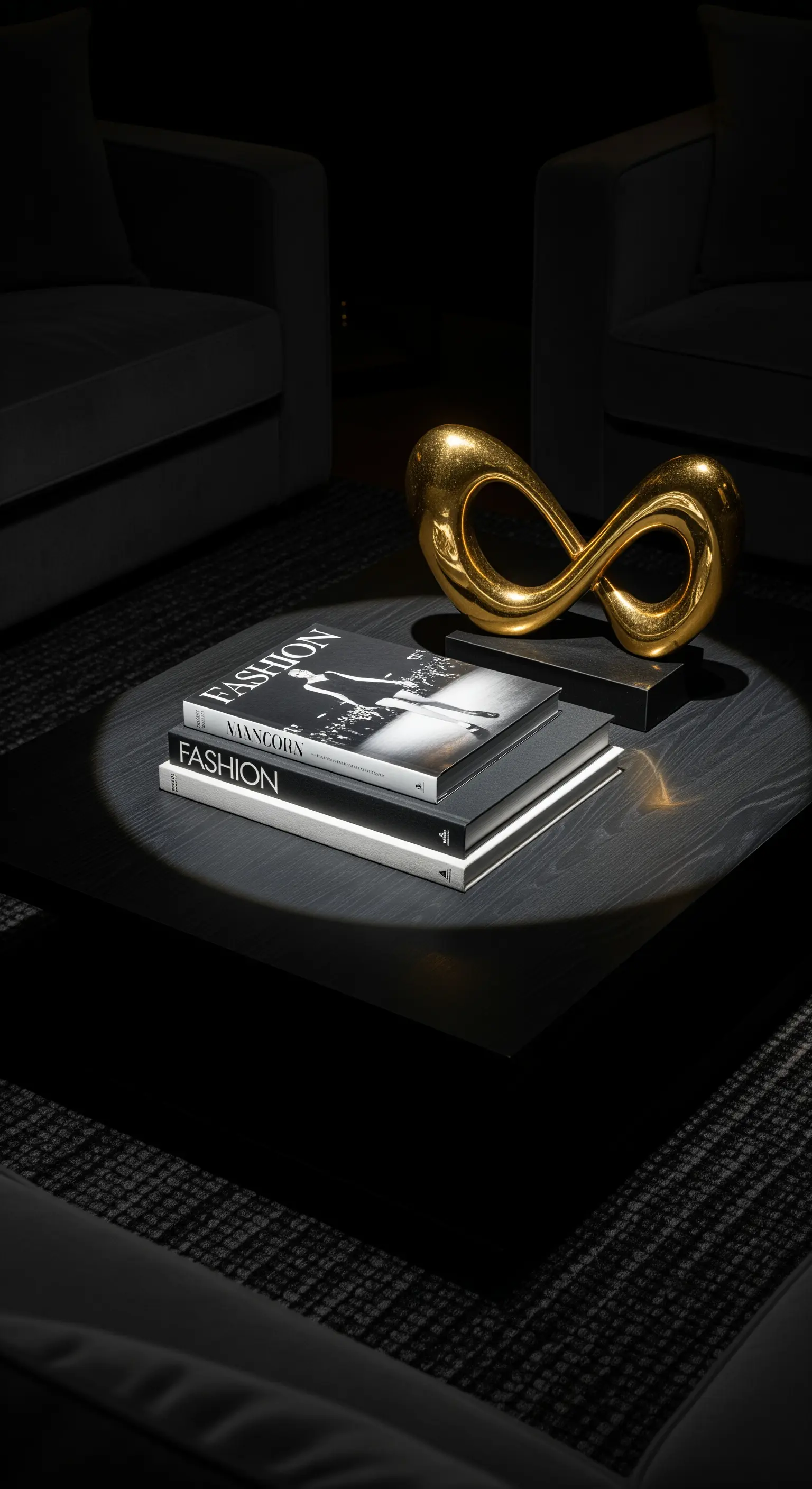 Dunkler Couchtisch mit Fashion-Büchern und goldener Skulptur, von Decken-Spotlight beleuchtet