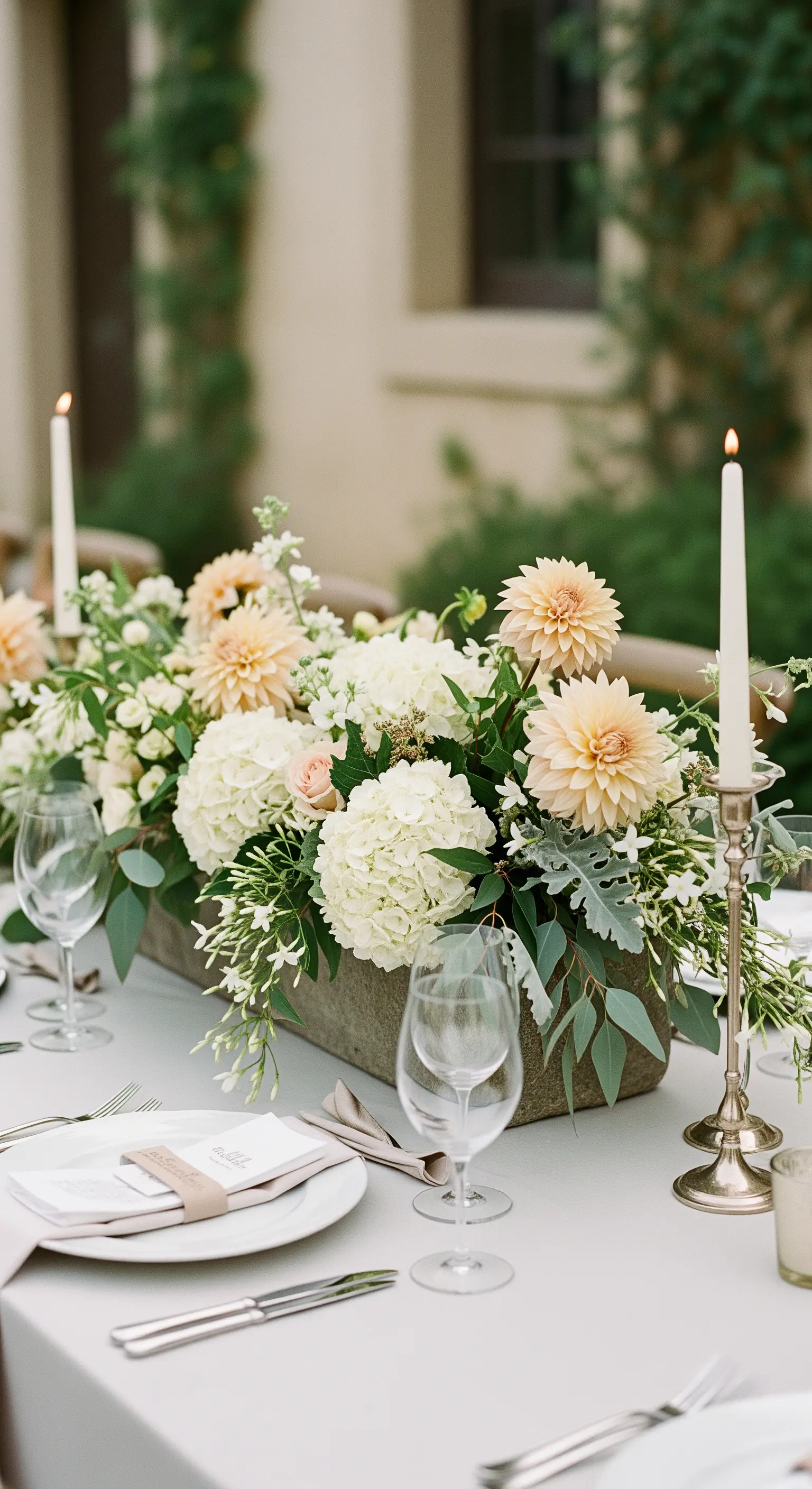 Längliches Blumengesteck mit Hortensien und Dahlien in einem grauen Steintrog auf einer Hochzeitstafel