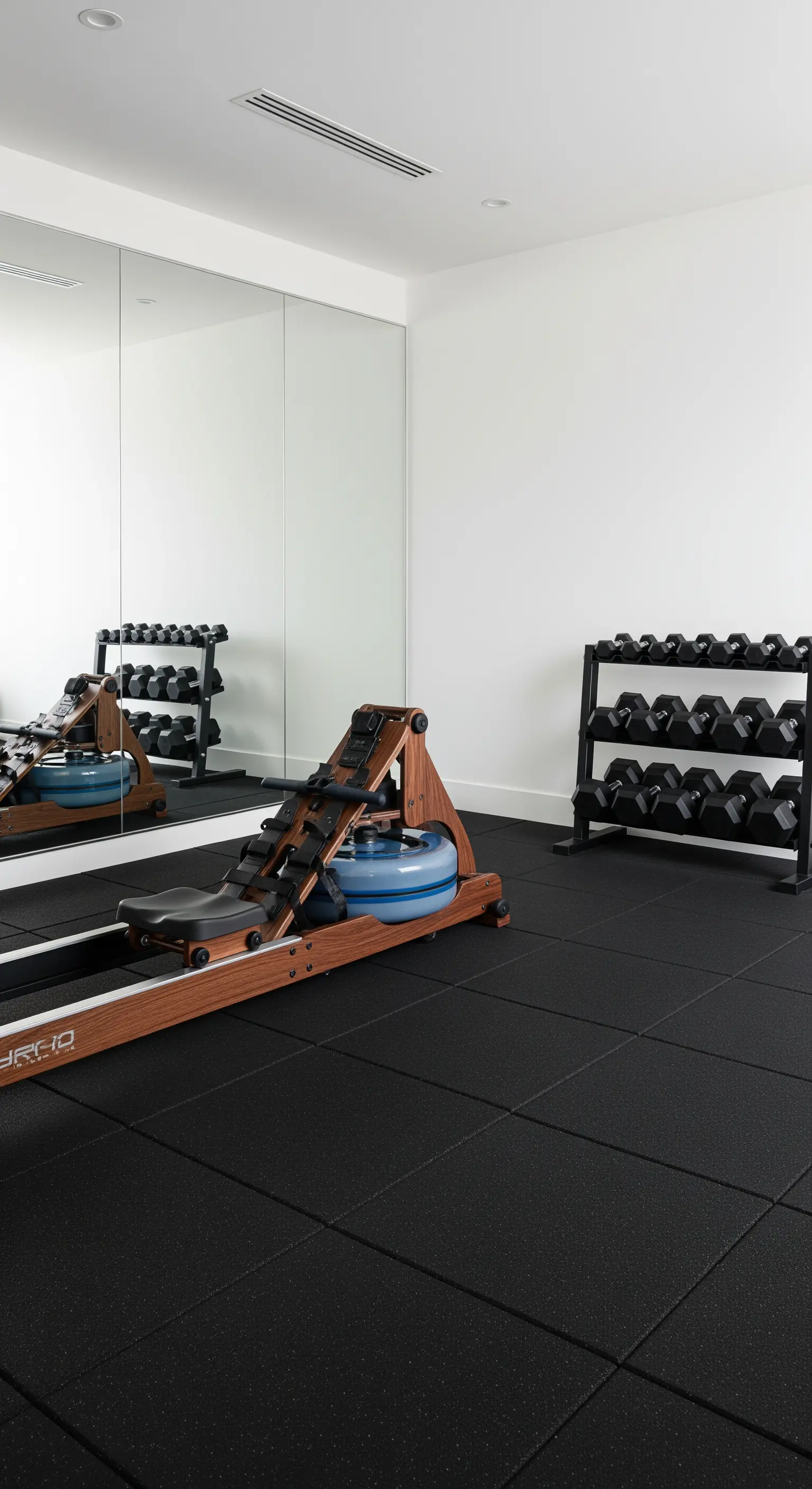 Minimalistisches Home-Gym mit Spiegelwand und ordentlich verstauten Hanteln.