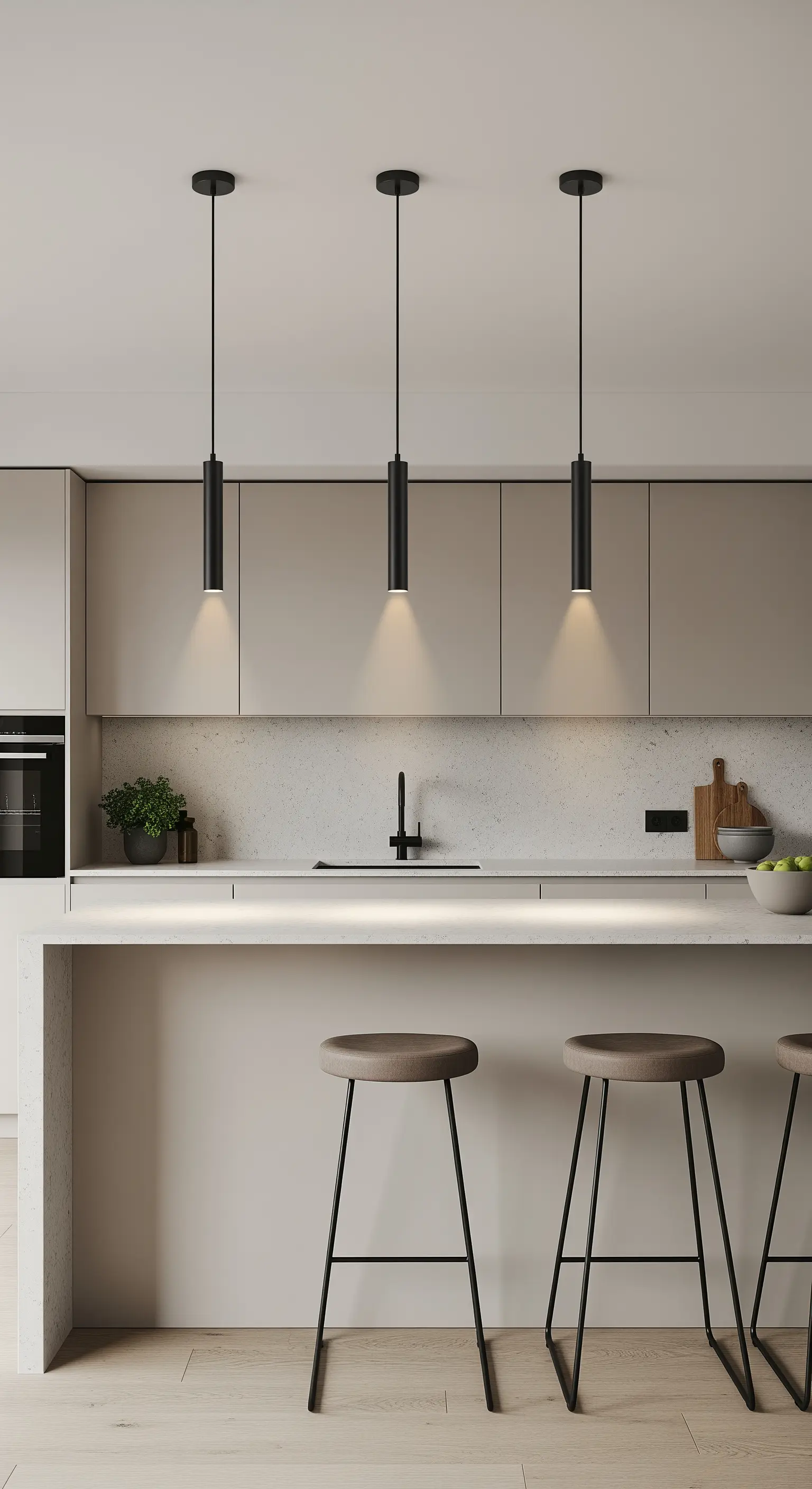 Drei schmale, schwarze Pendelleuchten hängen in einer Reihe über einer modernen Kücheninsel.