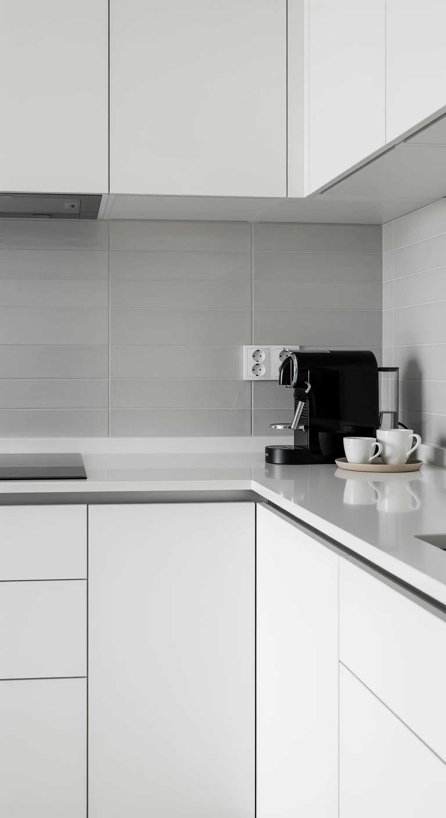 Eine saubere, weiße Küchenzeile mit einer organisierten Kaffeemaschine und Tassen.