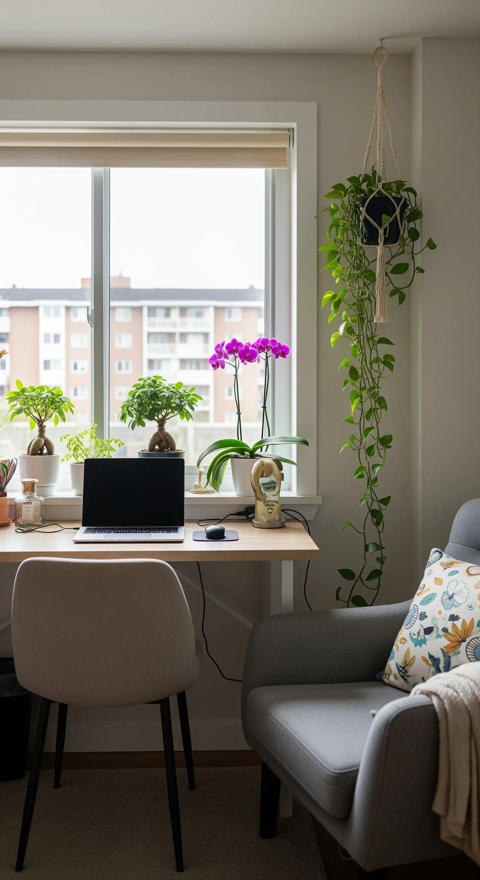 Ein kleiner Schreibtisch vor einem Fenster, dekoriert mit Bonsais, einer Orchidee und einer Hängepflanze.