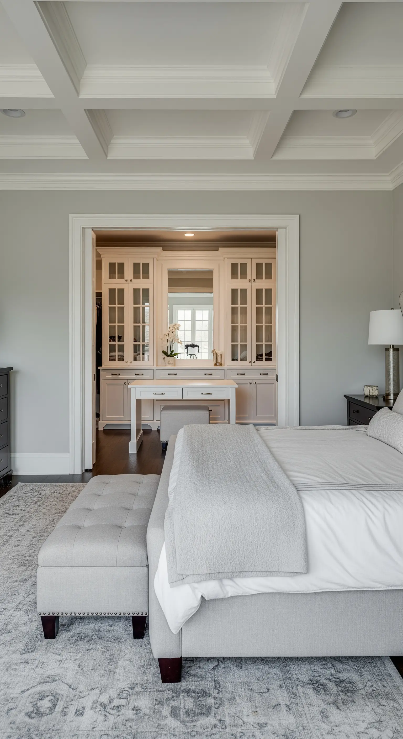 Blick vom Bett in einen klassischen, weißen begehbaren Kleiderschrank mit Schminktisch