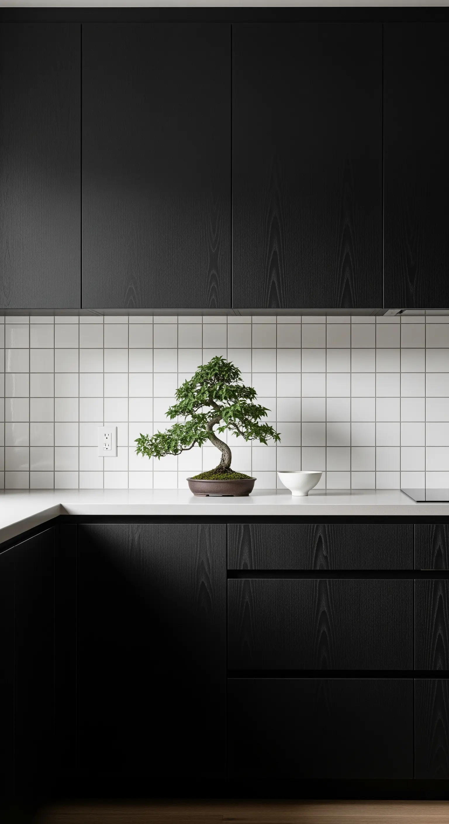 Dunkle, minimalistische Küche mit einem zentral platzierten Bonsai-Baum auf der Arbeitsplatte.