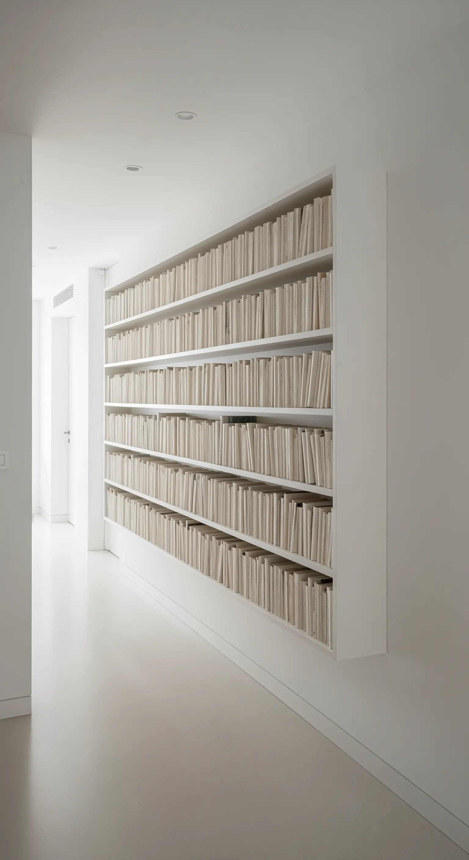 Wandhohes, eingebautes Bücherregal, bei dem die Bücher mit den Seiten nach vorne stehen.