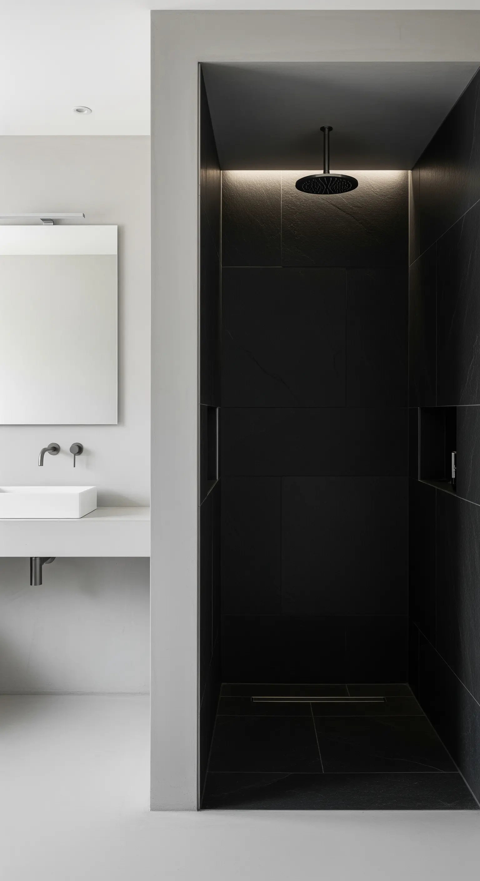 Moderne Walk-in-Dusche mit großen, schwarzen Fliesen und indirekter Beleuchtung.