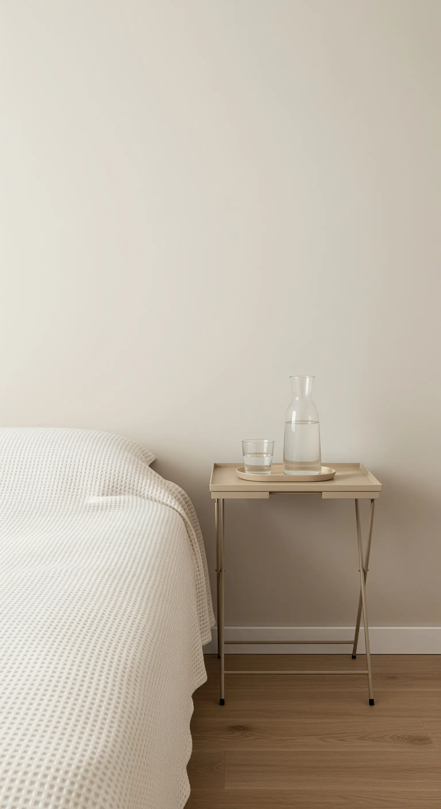 Schlichter, beigefarbener Klapptisch mit einem Tablett als minimalistischer Nachttisch.