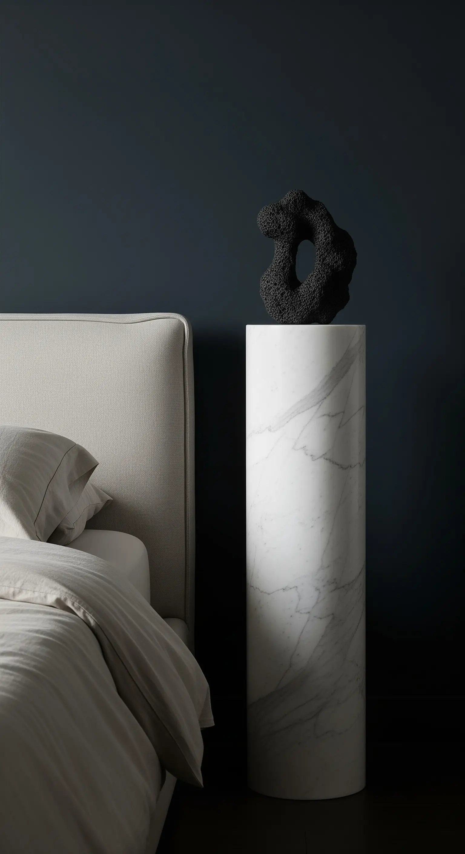 Hohe, zylindrische Marmorsäule als Nachttisch mit einer schwarzen Skulptur.