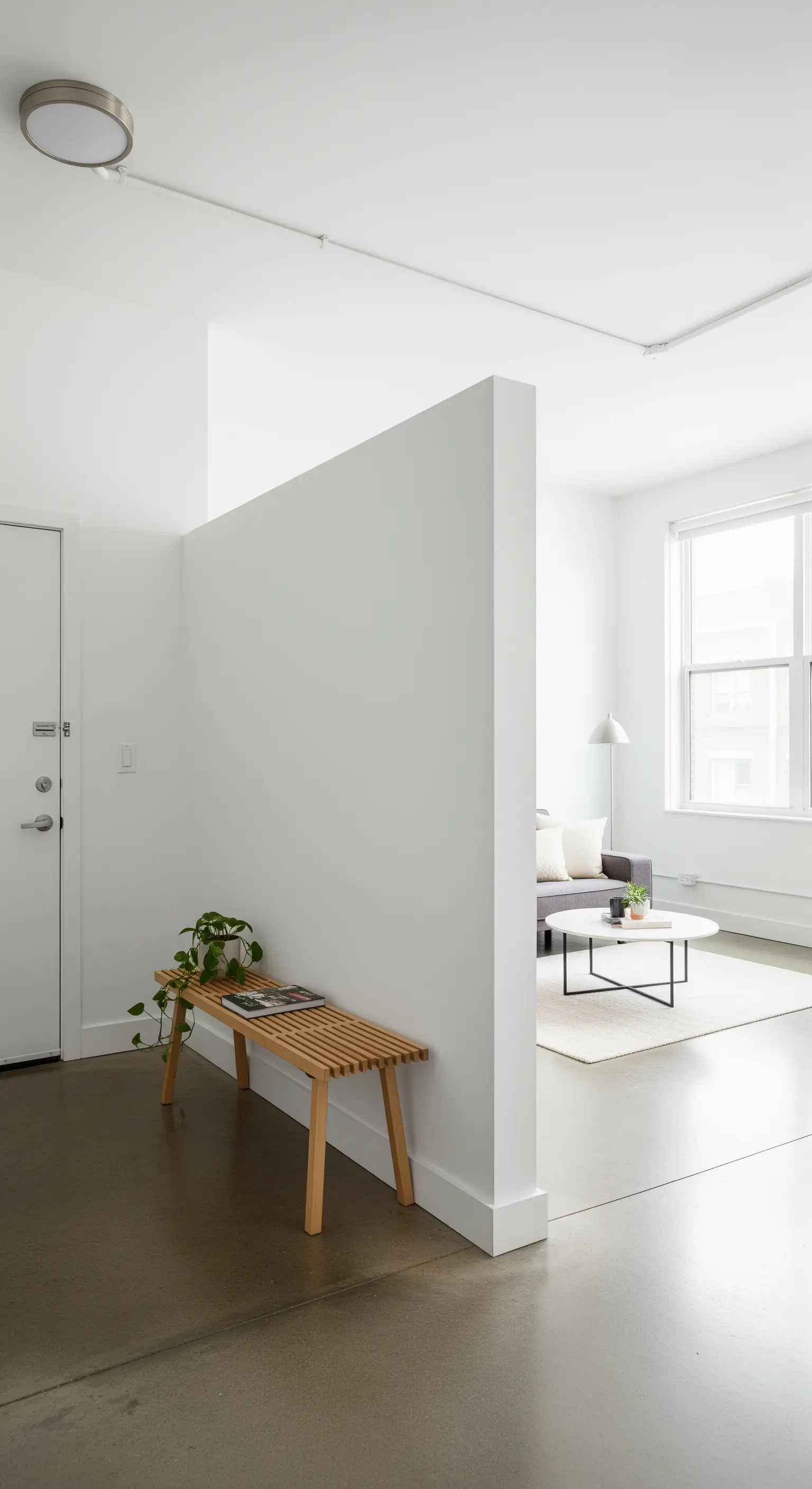 Halbhohe weiße Wand trennt den Eingangsbereich vom Wohnzimmer in einem Loft