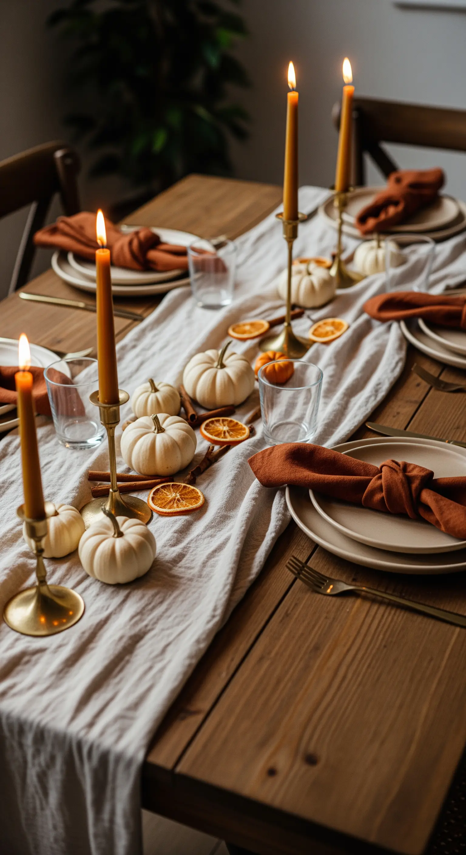 Herbstlich gedeckter Esstisch mit weißen Kürbissen, Kerzen und Orangenscheiben.