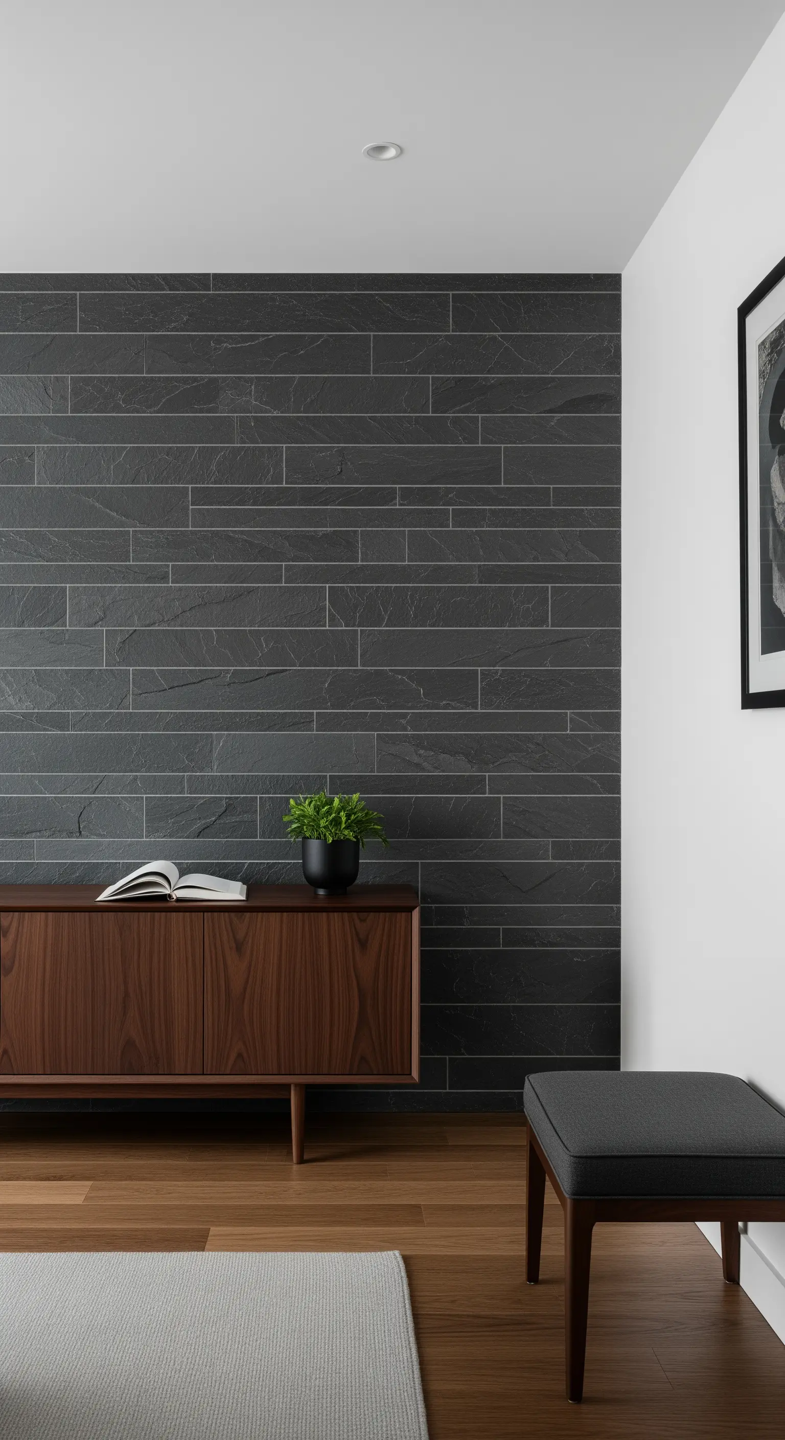 Akzentwand aus dunklen Schieferfliesen hinter einem Sideboard aus Walnussholz.