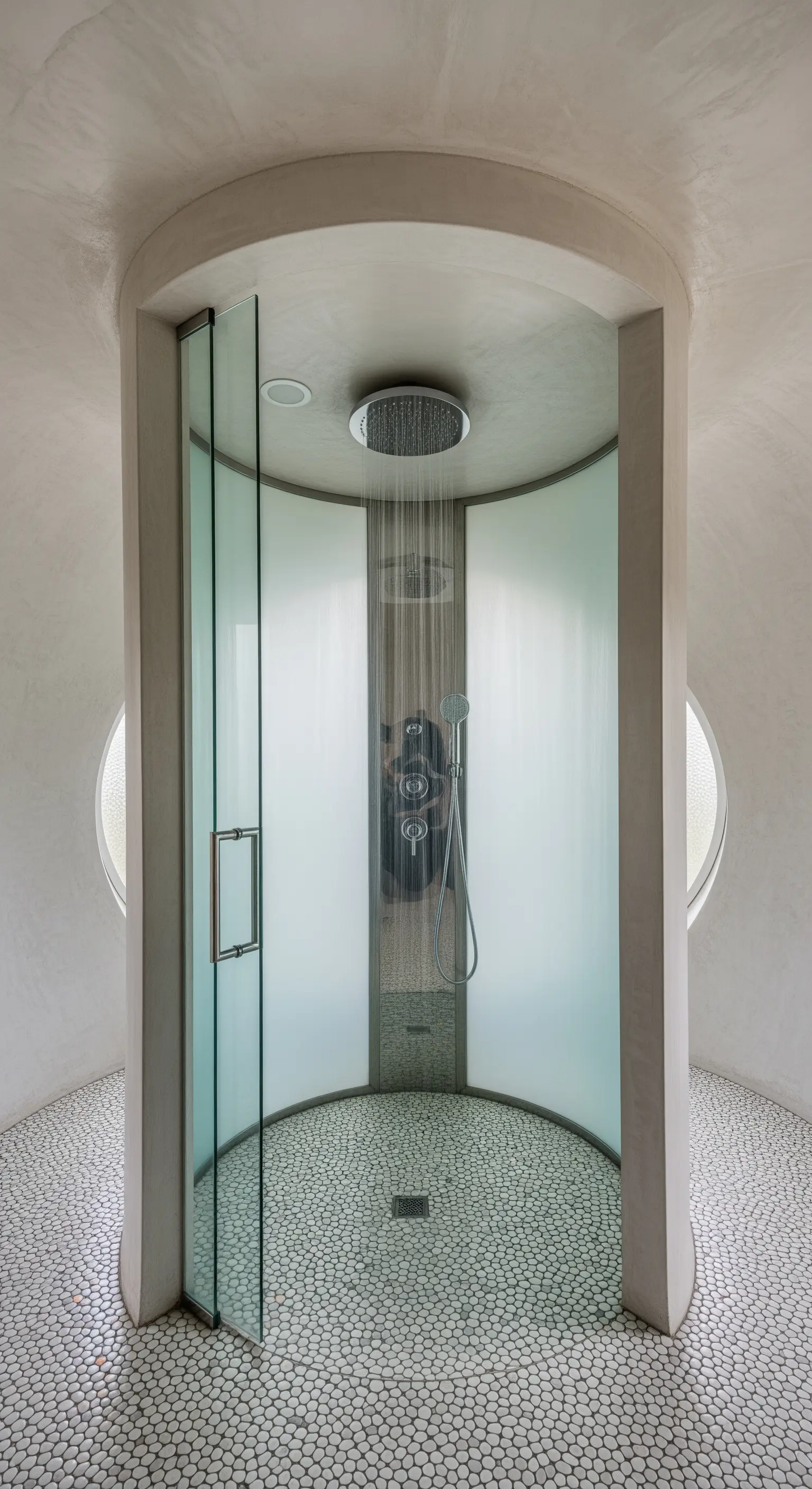 Futuristische, zylindrische Duschkabine mit gebogenem Glas und Mosaikboden