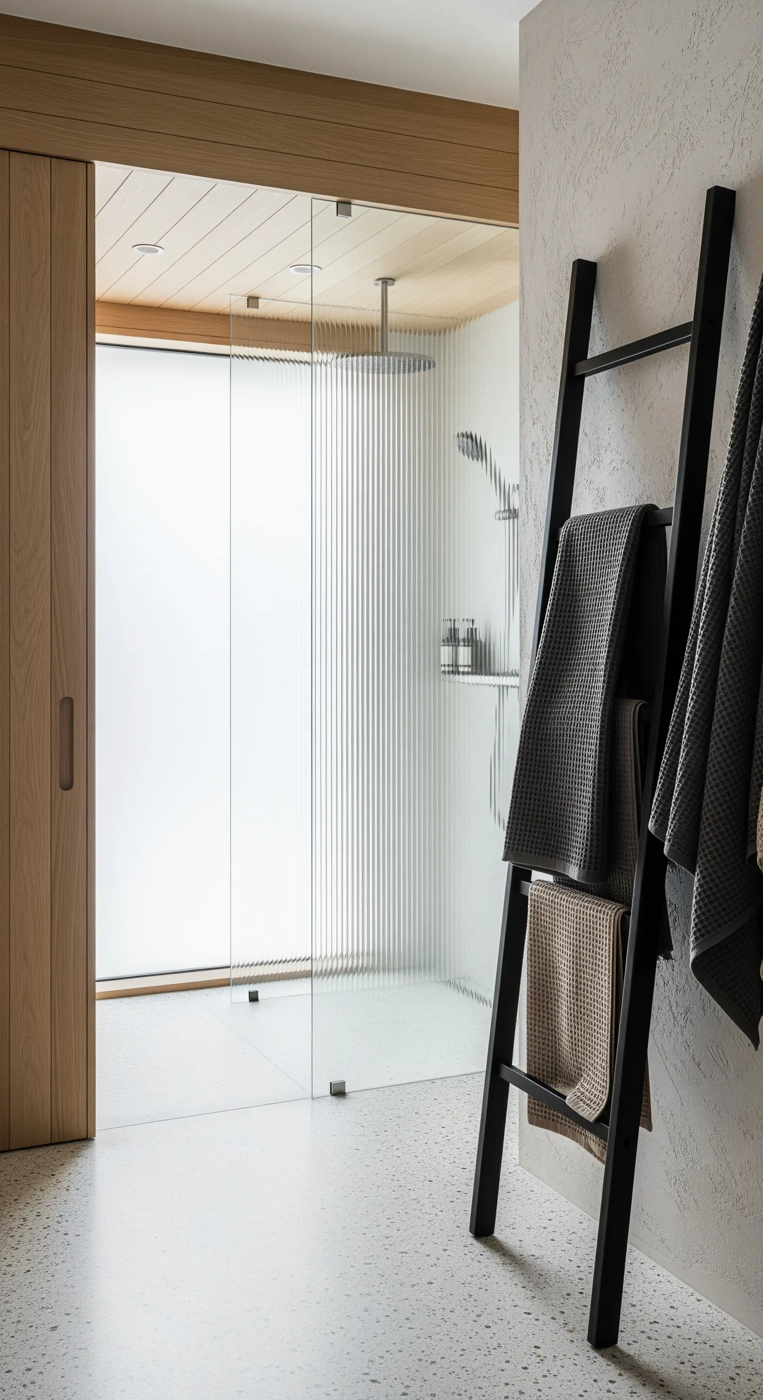 Schwarze Handtuchleiter als minimalistischer Akzent in einem Bad mit texturierten Wänden.