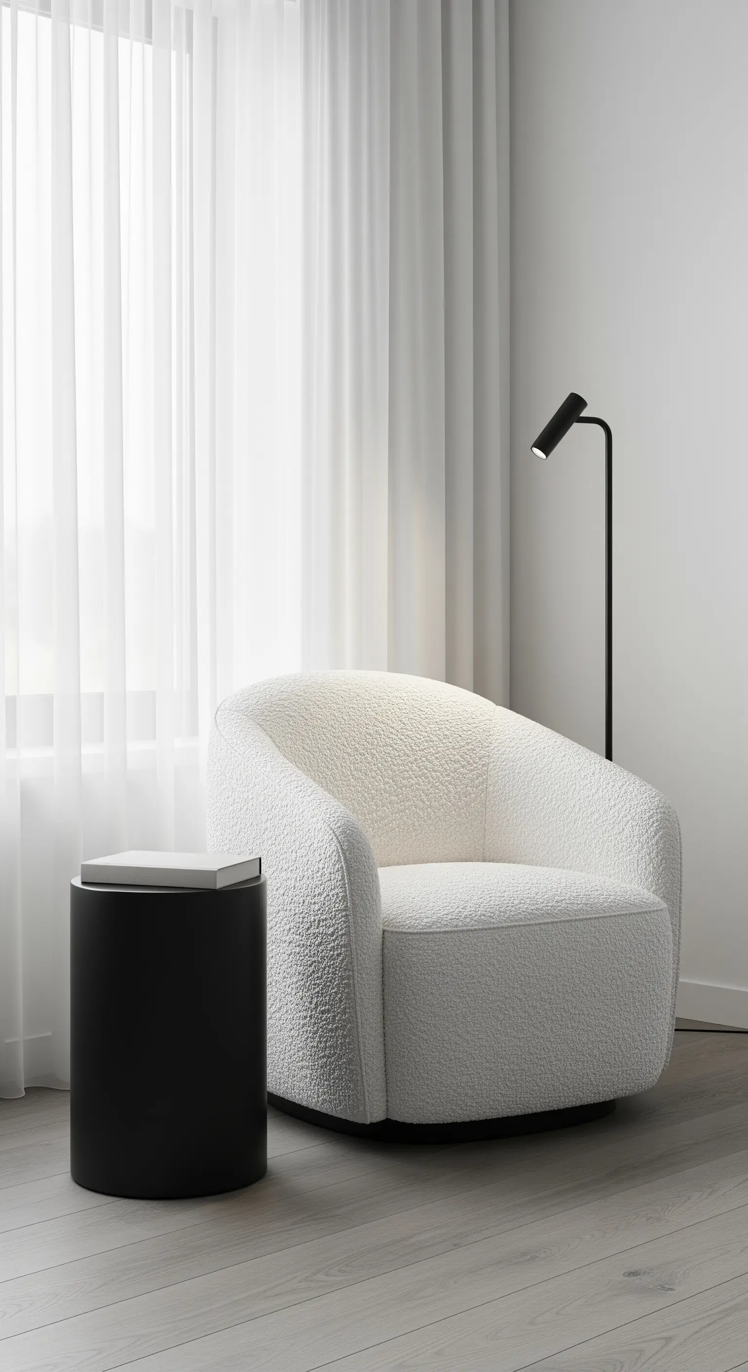 Leseecke mit weißem Bouclé-Sessel und schwarzem, zylindrischem Beistelltisch.