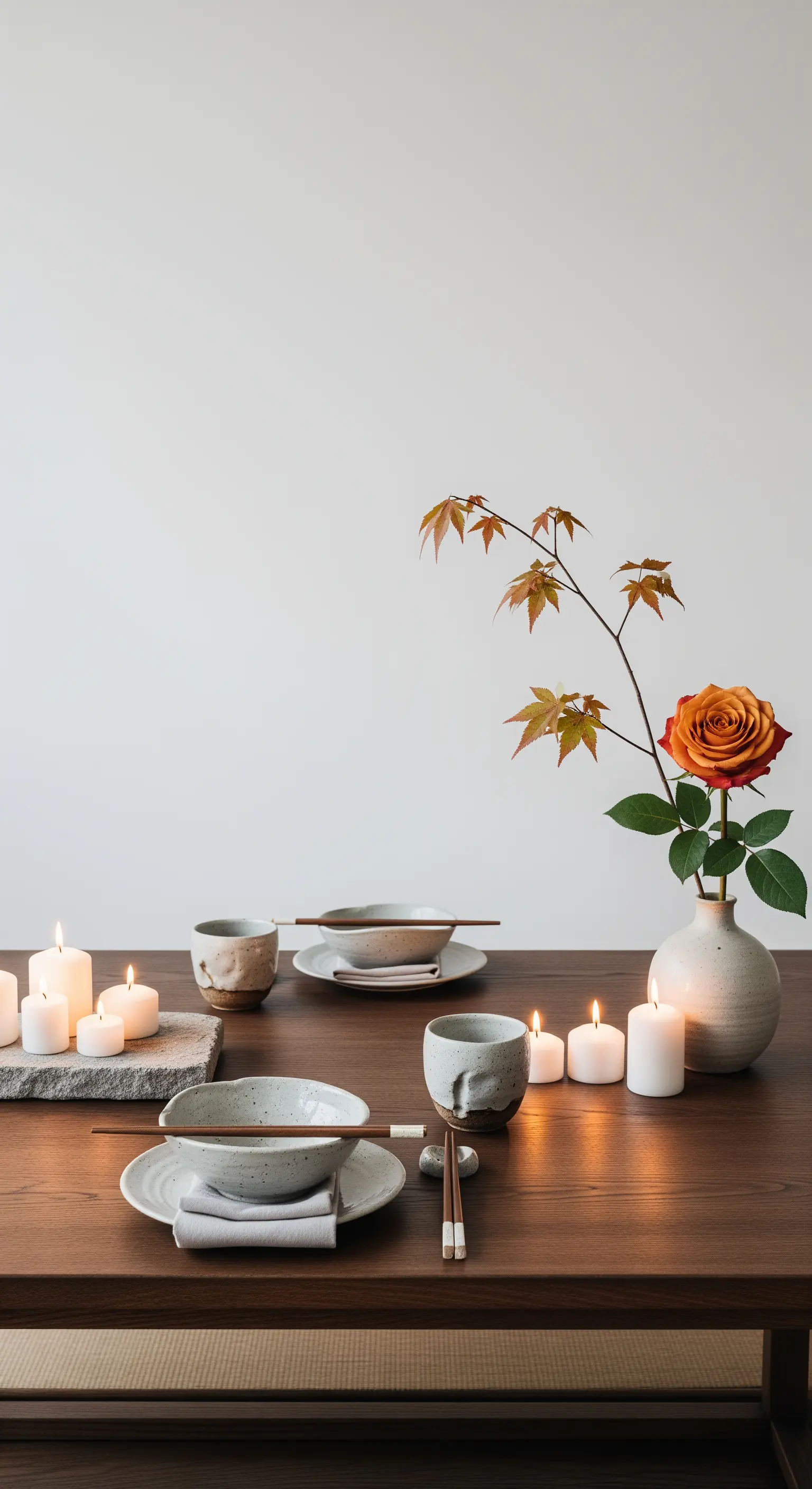 Minimalistische Japandi-Tischdeko mit Keramik, einem Ahornzweig und einer Rose.