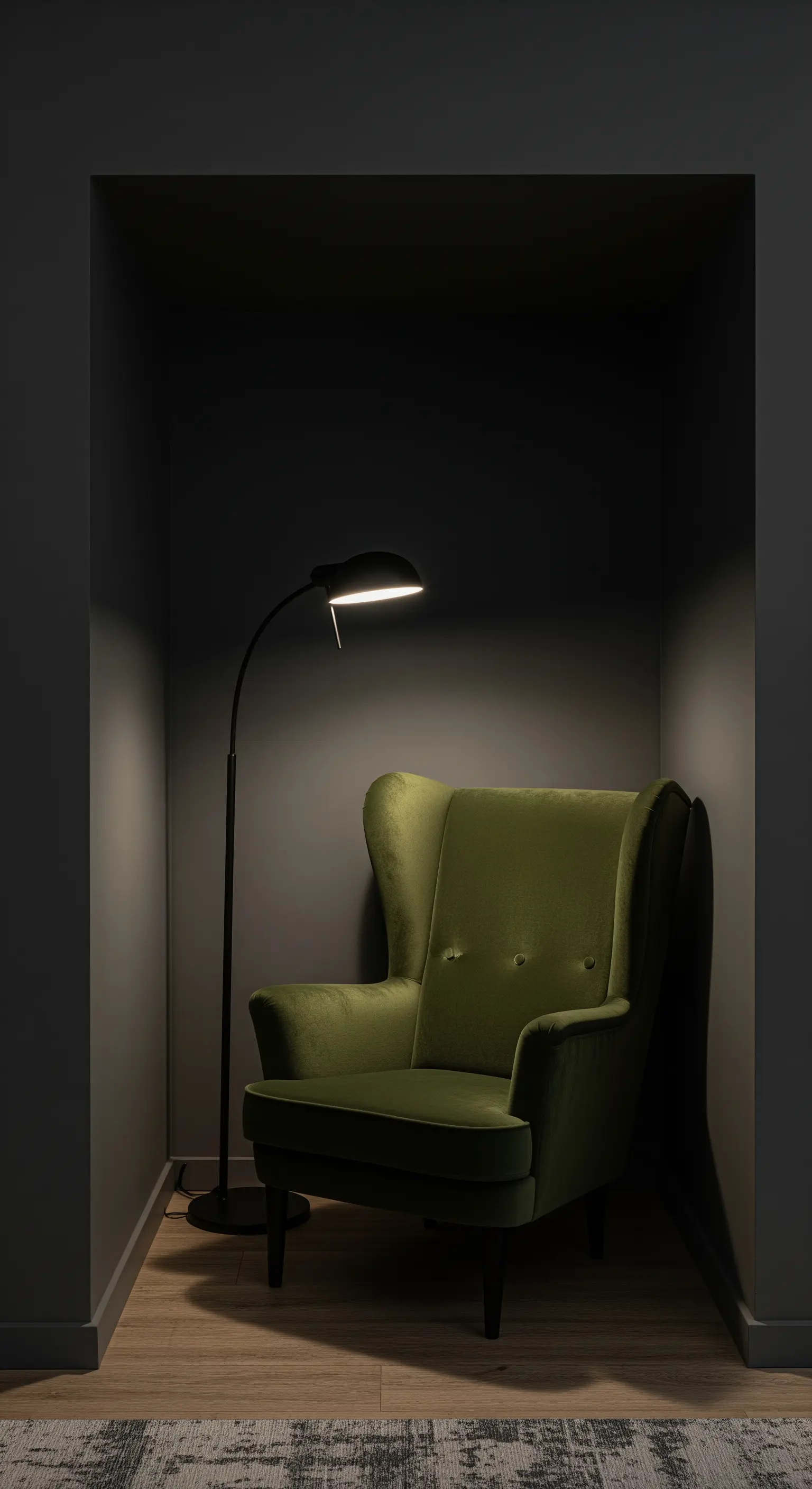 Ein Ohrensessel aus olivgrünem Samt steht in einer dunklen Nische, beleuchtet von einer Lampe