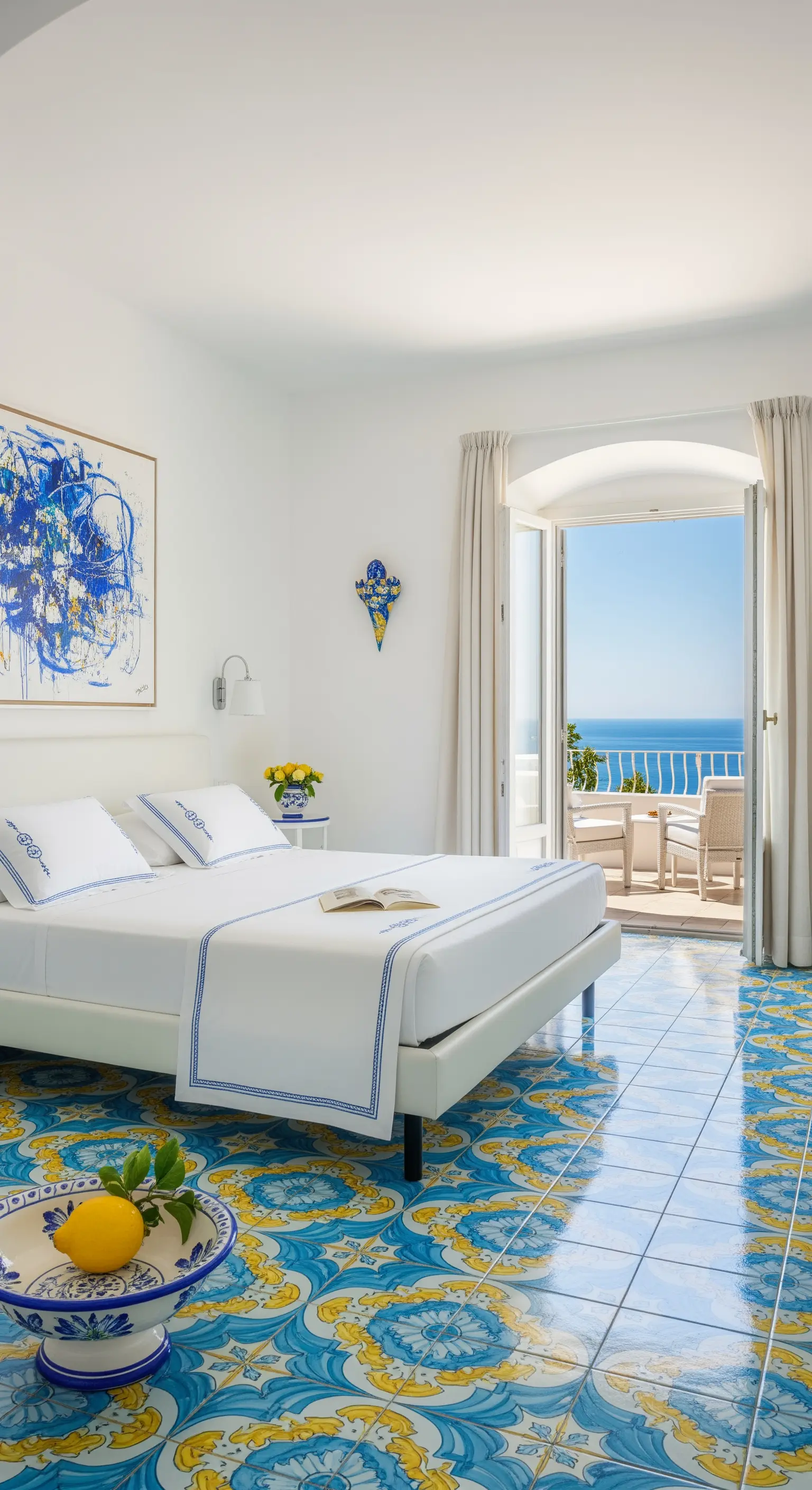 Helles Schlafzimmer im mediterranen Stil mit bunten Bodenfliesen und Meerblick.