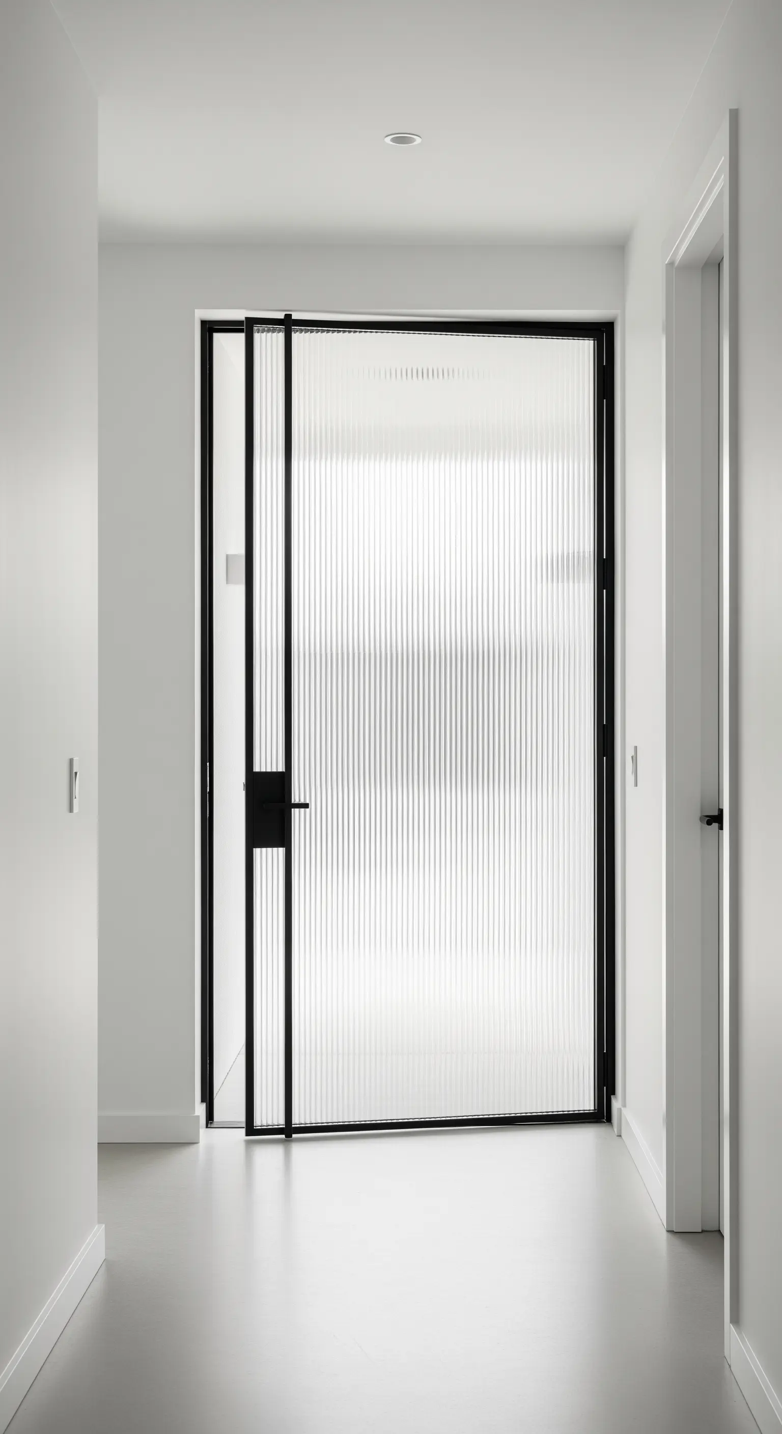 Moderne Tür aus Rillenglas mit schwarzem Metallrahmen in einem minimalistischen, weißen Flur.
