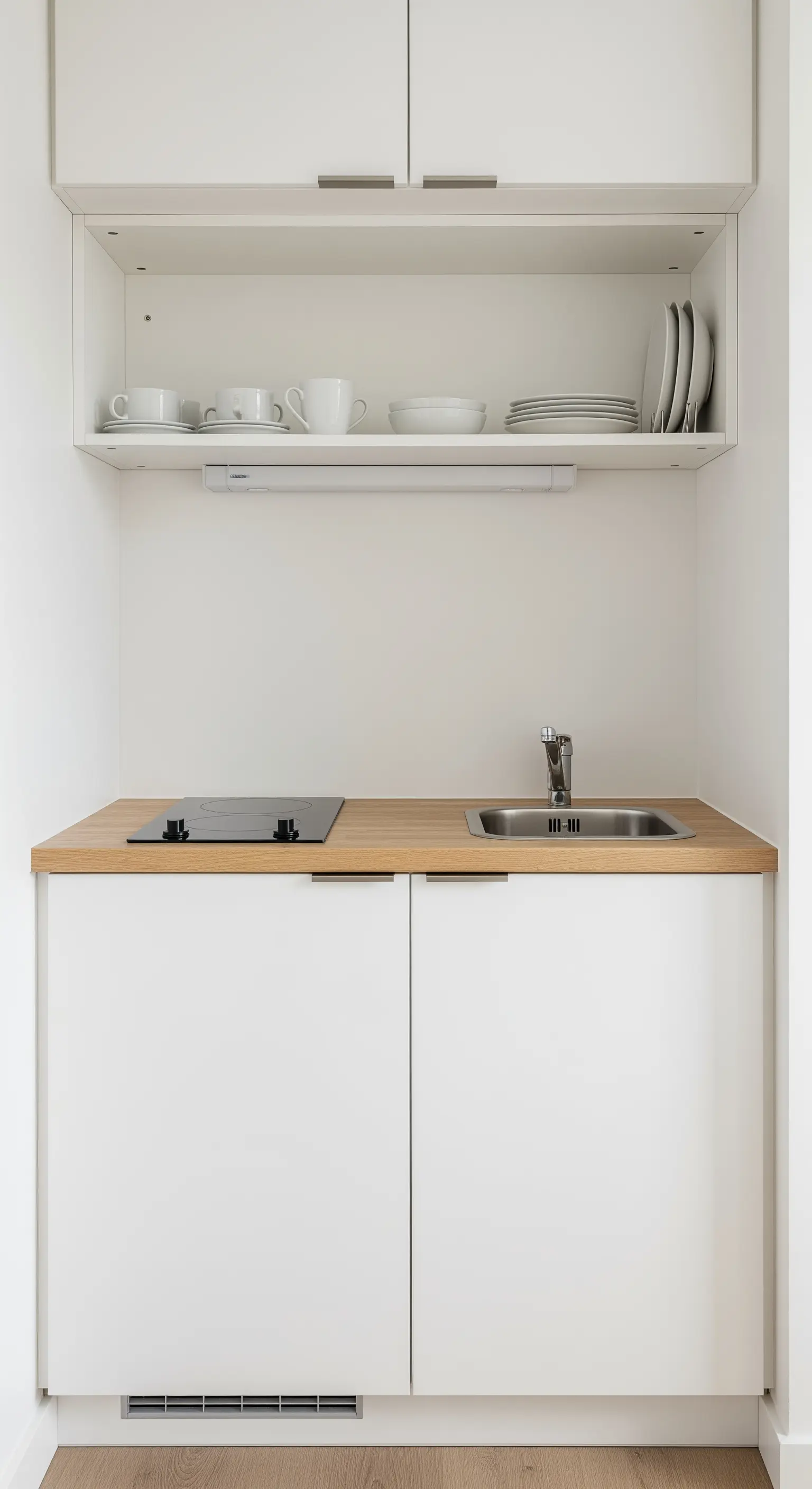 Kompakte, weiße Küchenzeile mit Holz-Arbeitsplatte und offenem Regal mit weißem Geschirr.
