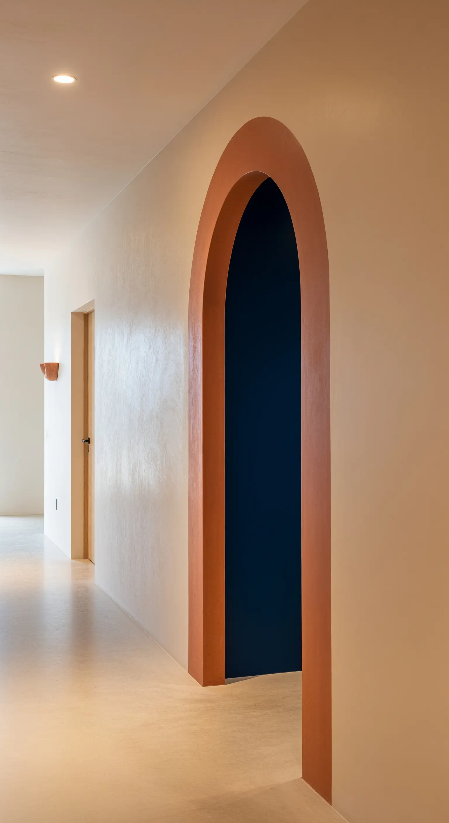 Rundbogen-Durchgang in Terrakotta als Akzent in einem cremefarbenen Flur.