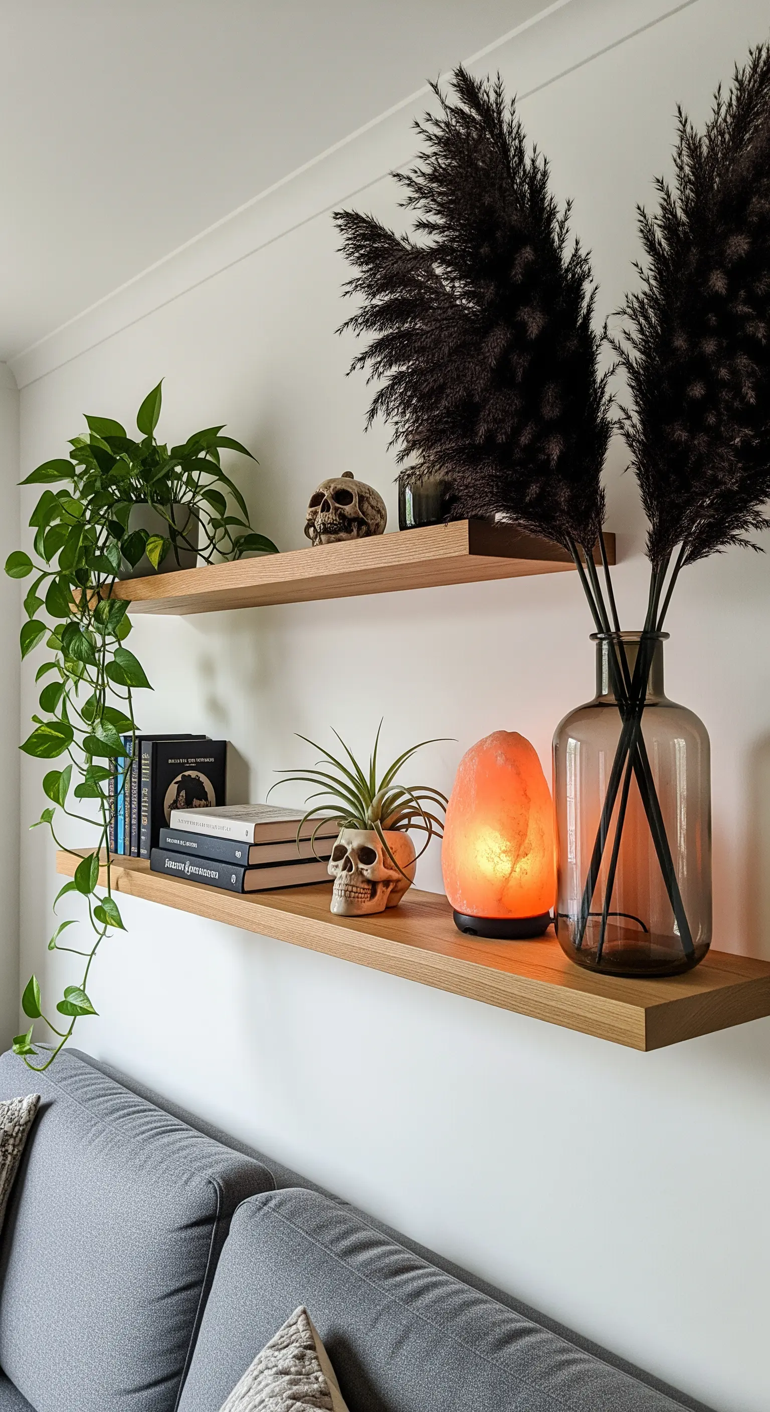 Regal-Deko mit schwarzem Pampasgras, Totenköpfen und einer leuchtenden Salzlampe.