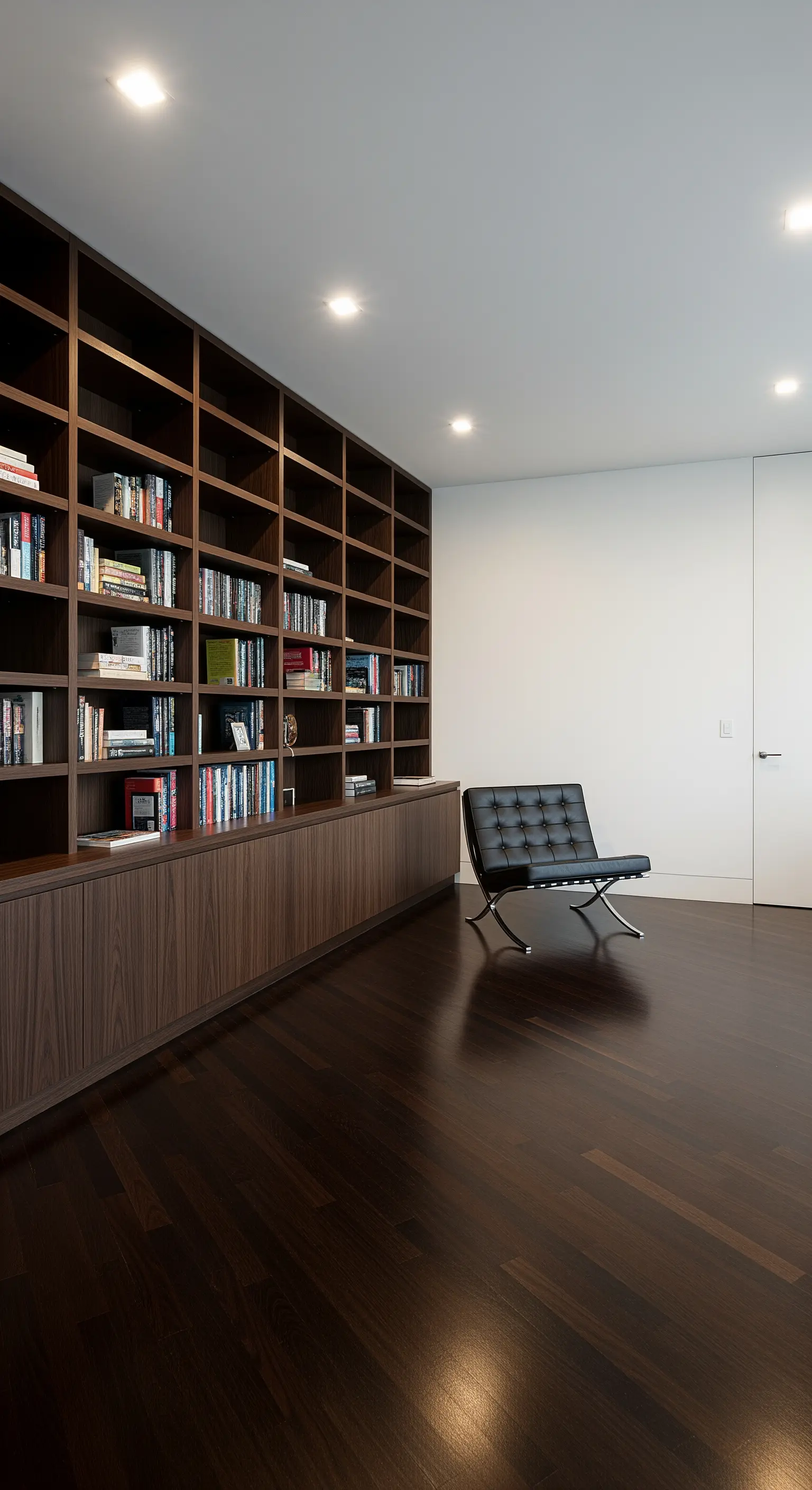 Elegantes Arbeitszimmer mit dunklem Holzboden, raumhohem Bücherregal und einem schwarzen Ledersessel