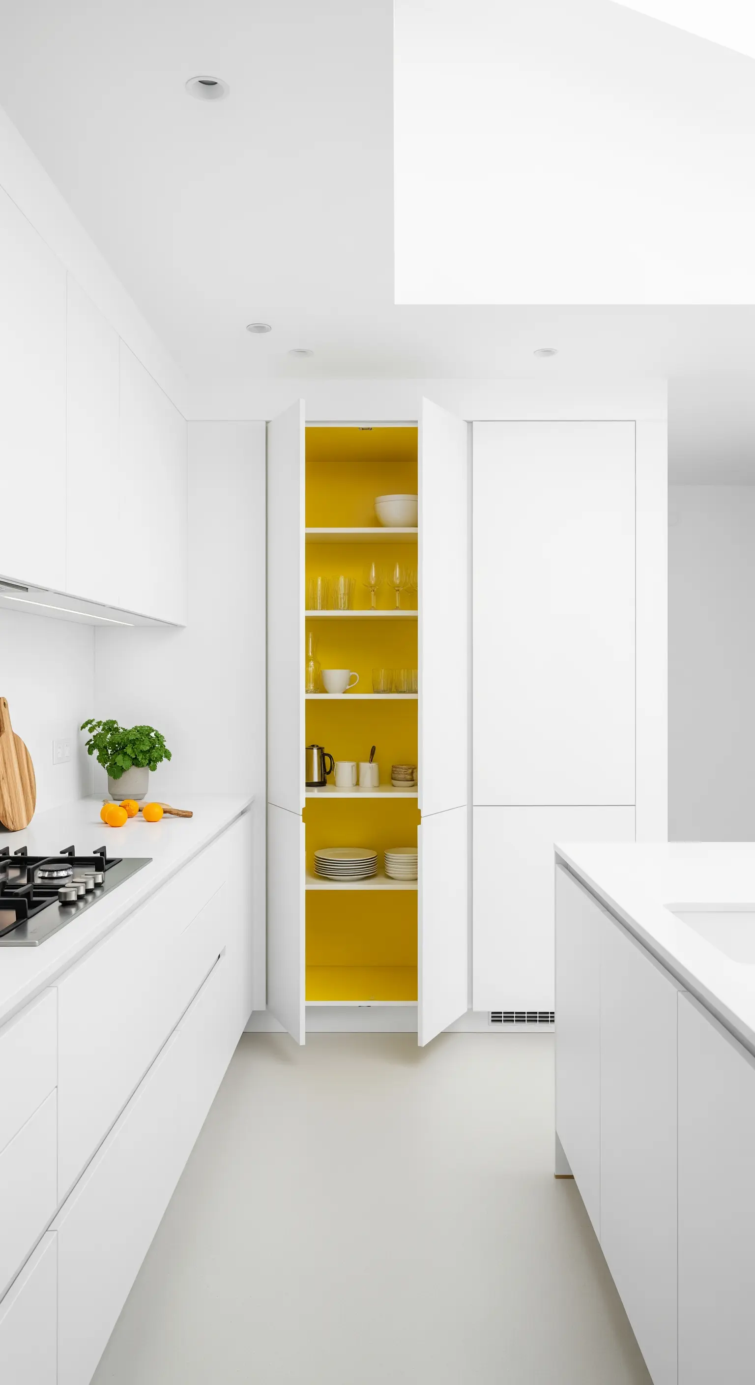Reinweiße Küche mit einem geöffneten Schrank, dessen Inneres leuchtend gelb ist