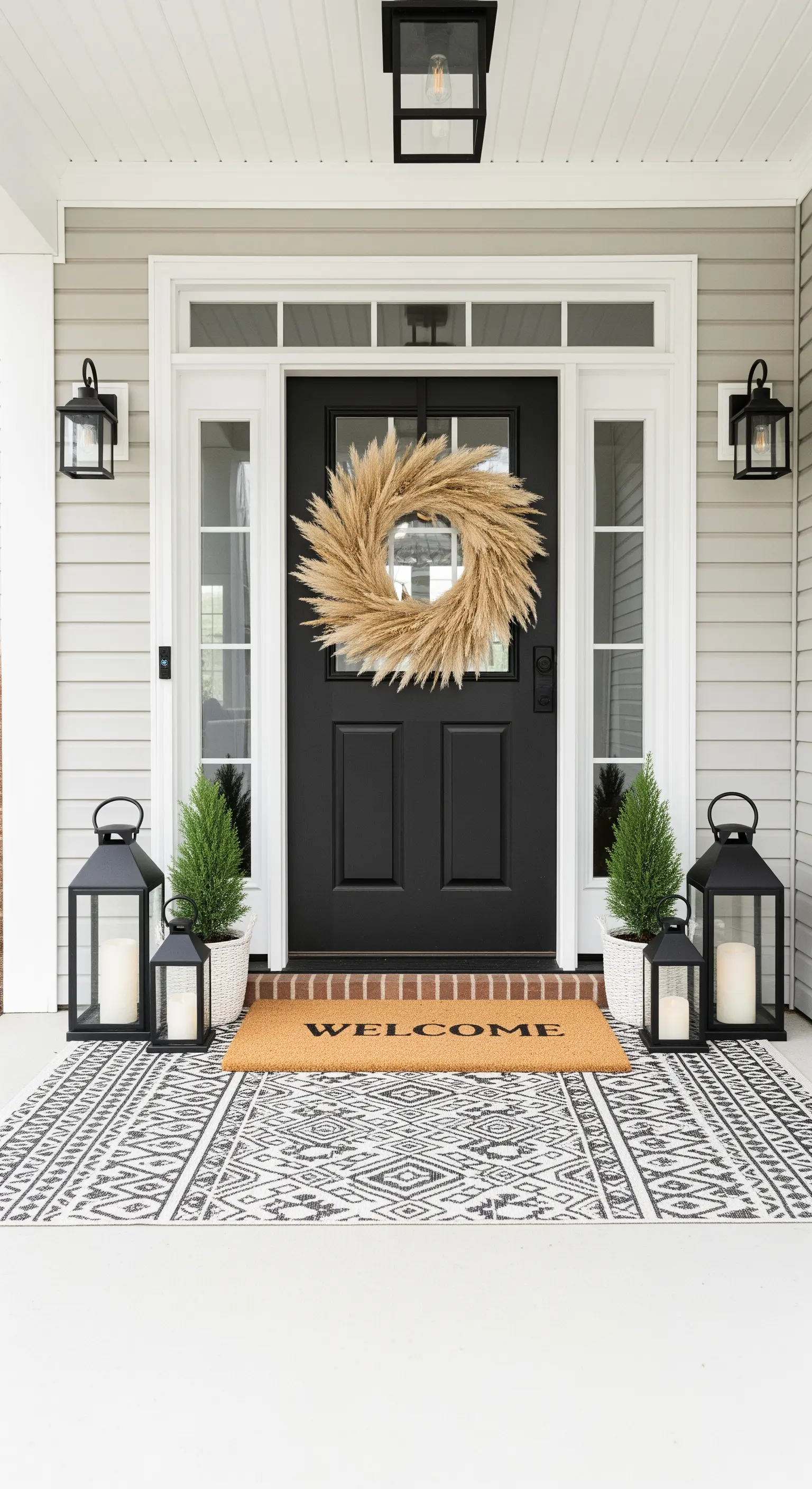 Haustür mit großem Pampasgras-Kranz, schwarzen Laternen und gemustertem Teppich