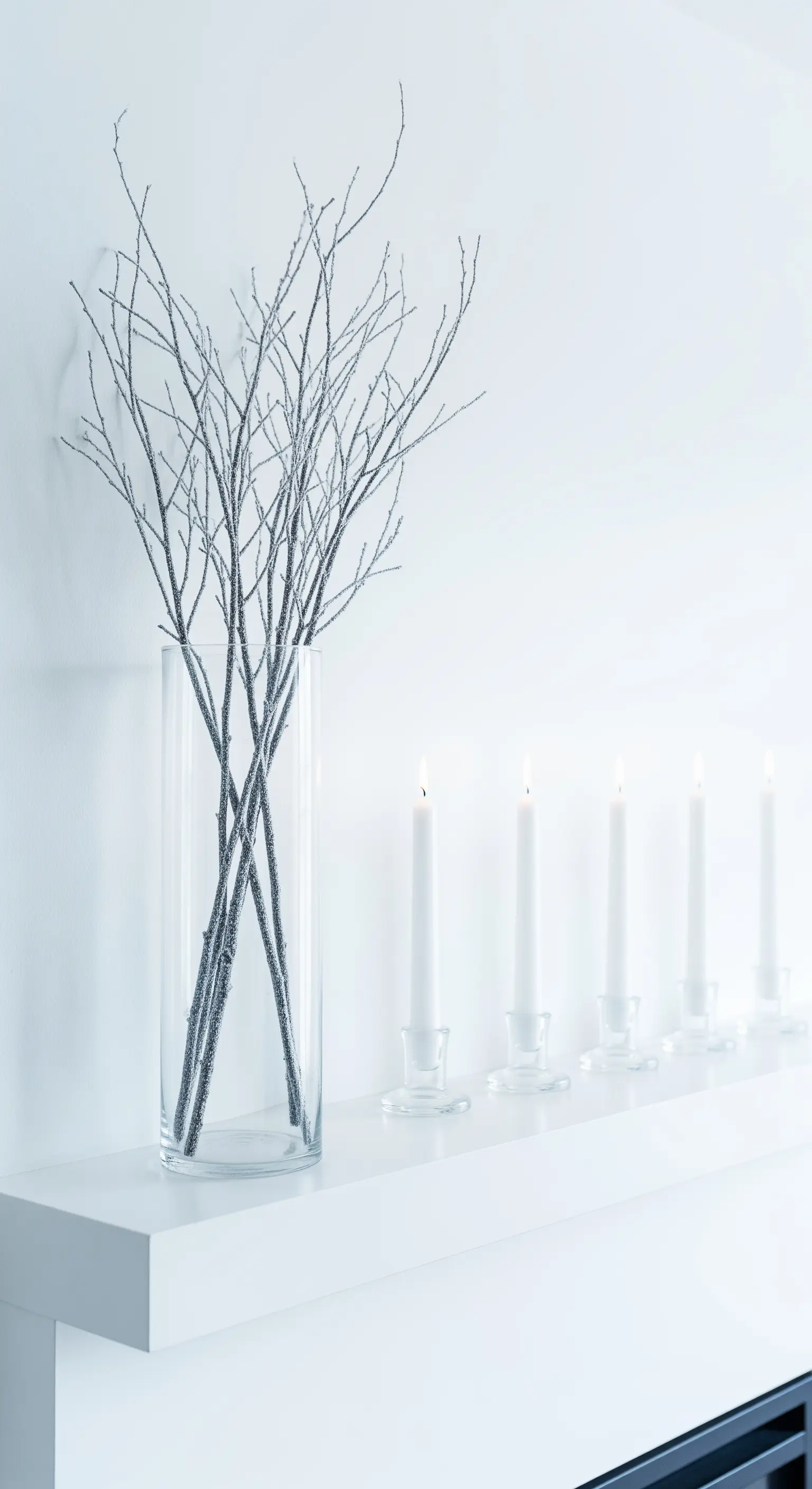 Minimalistische Winterdeko für den Kamin in Weiß mit vereisten Zweigen und Kerzen.