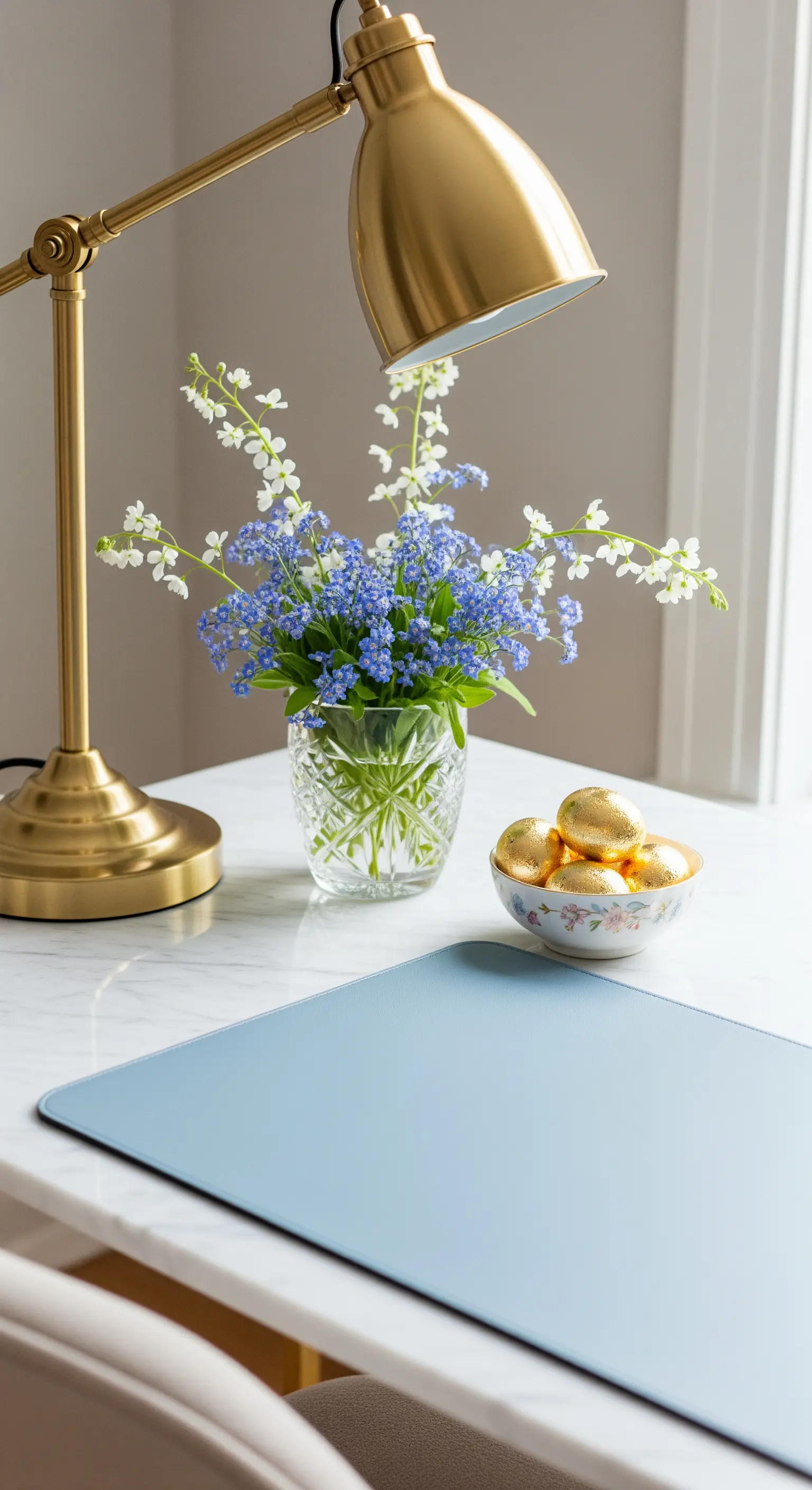 Schreibtisch mit goldener Lampe, blauen Blumen und goldenen Ostereiern.