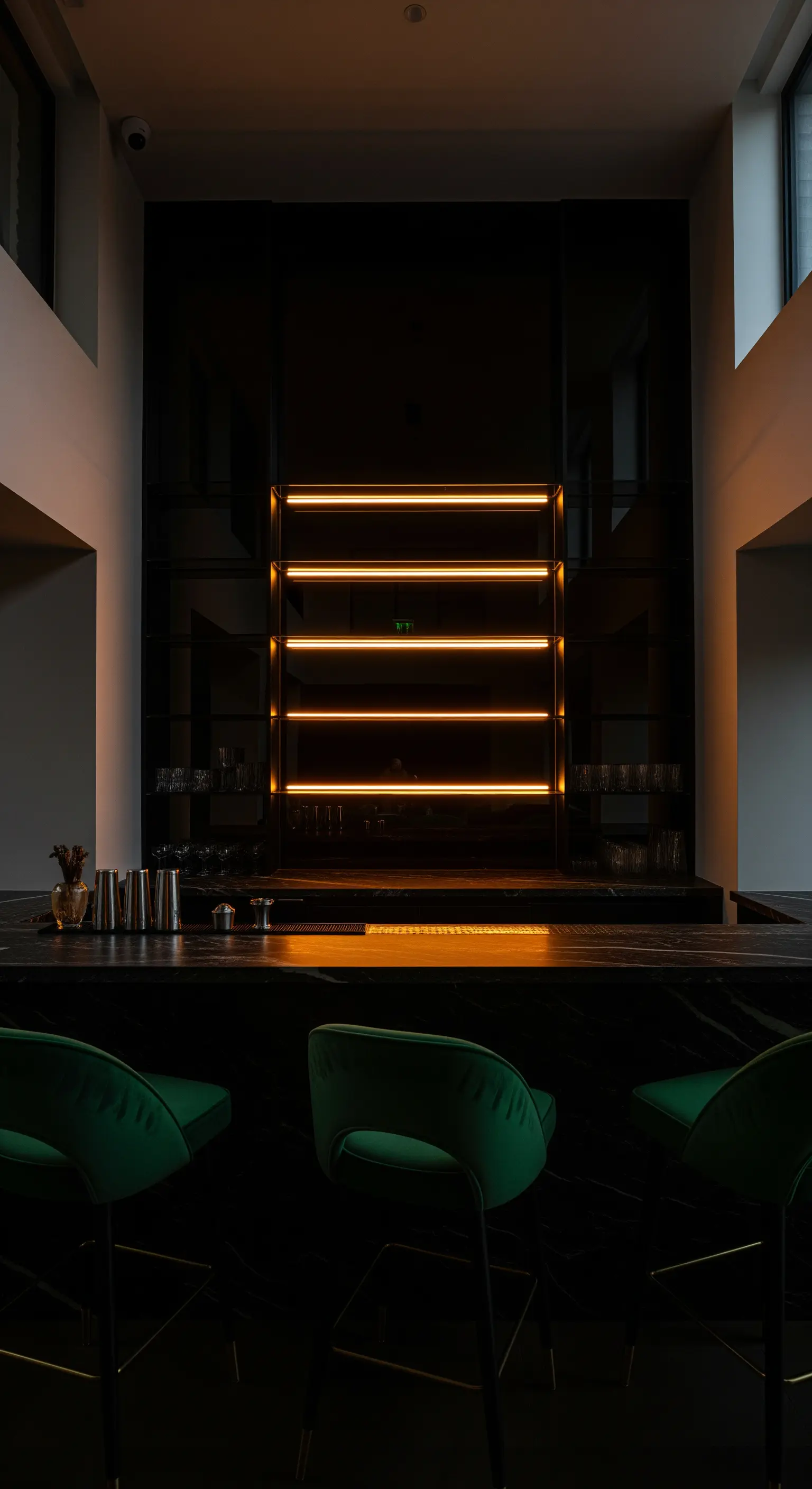 Hausbar mit schwarzer Hochglanzwand, hinterleuchtetem Regal und grünen Samthockern